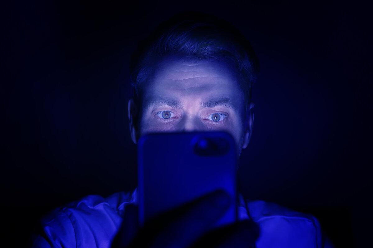 Internetsucht. Mann benutzt nachts Smartphone. In Blau getönt