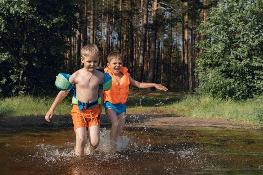 Zwei Kleinkinder laufen in den See rein