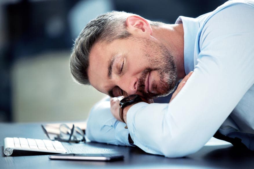 Geschäftsmann auf dem Bürotisch beim Mittagsschlaf