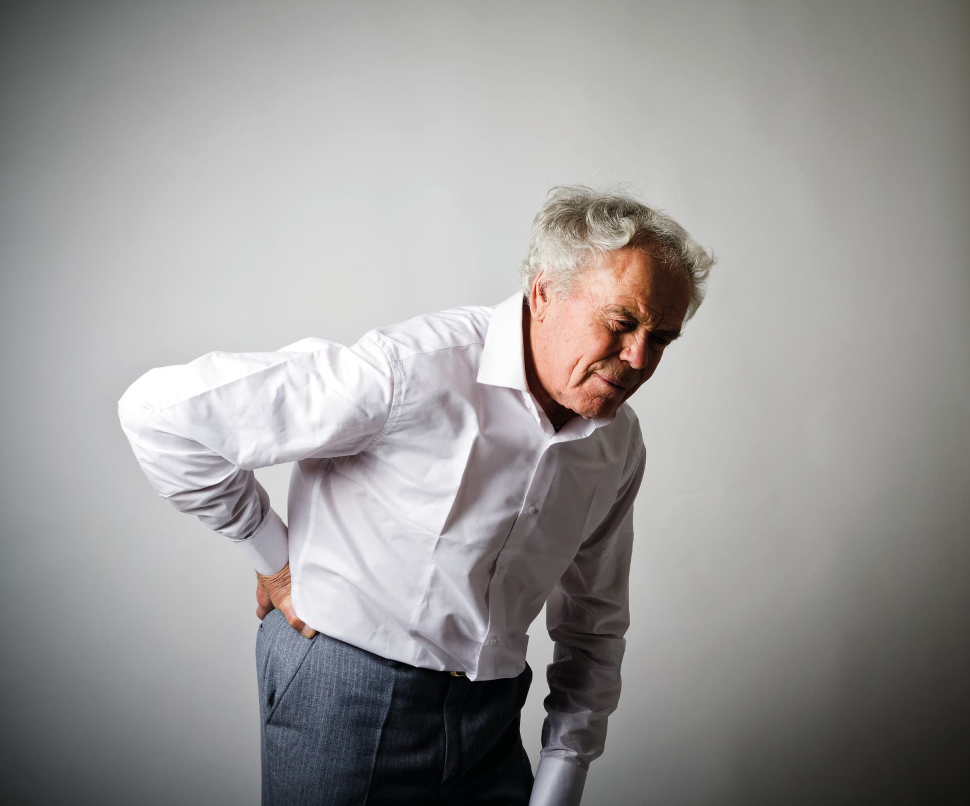 Old man in white is having a back pain.