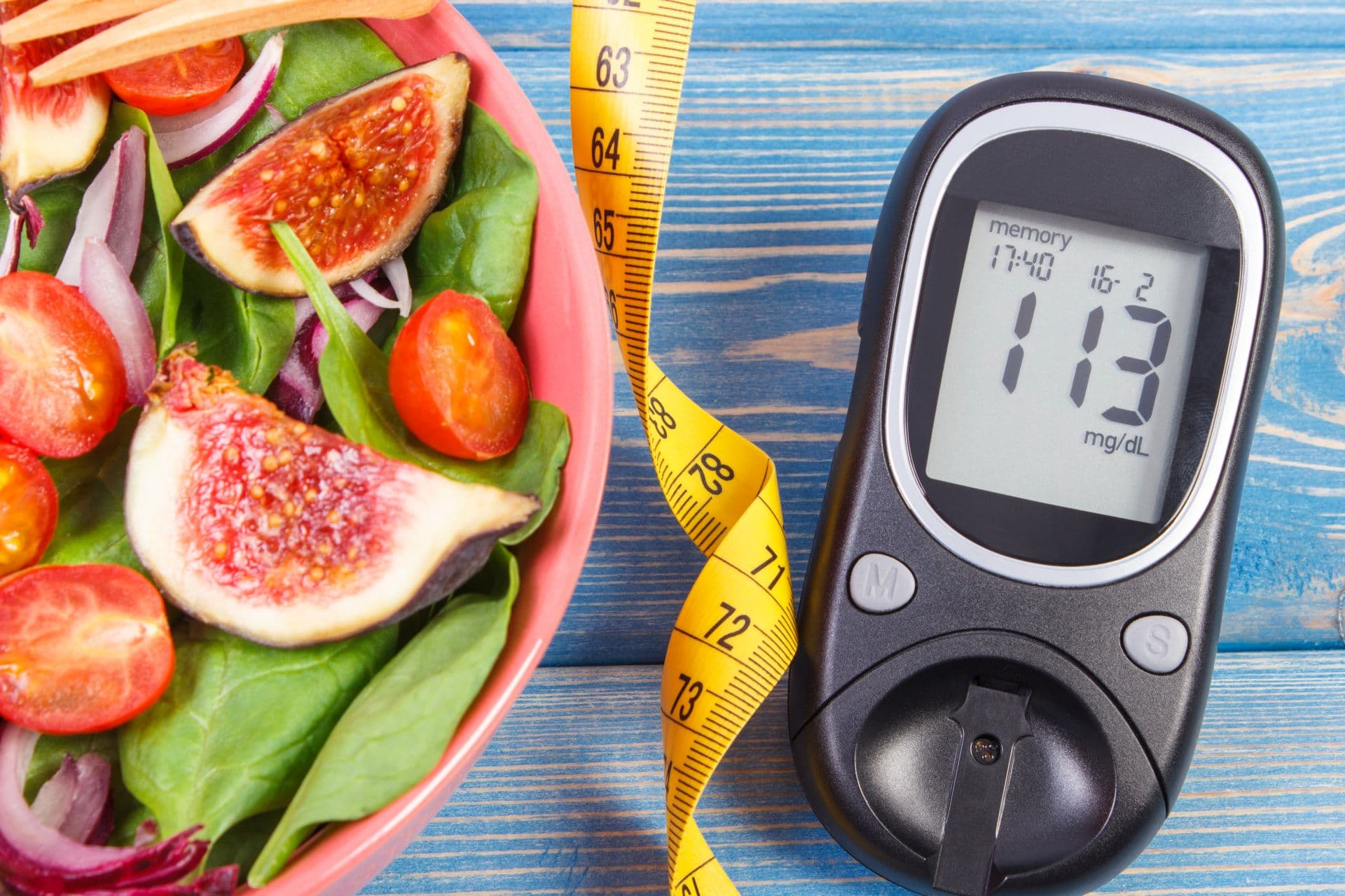 Fruit and vegetable salad and glucose meter with tape measure, concept of diabetes, slimming and healthy nutrition