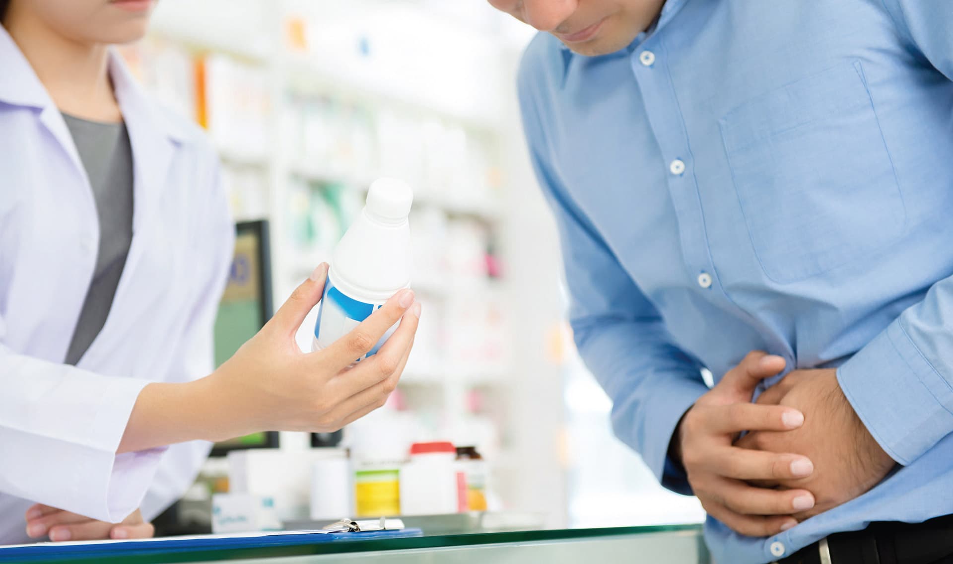 Eine Apothekerin erklärt einem Kunden etwas anhand einer Mediakmentenflasche.