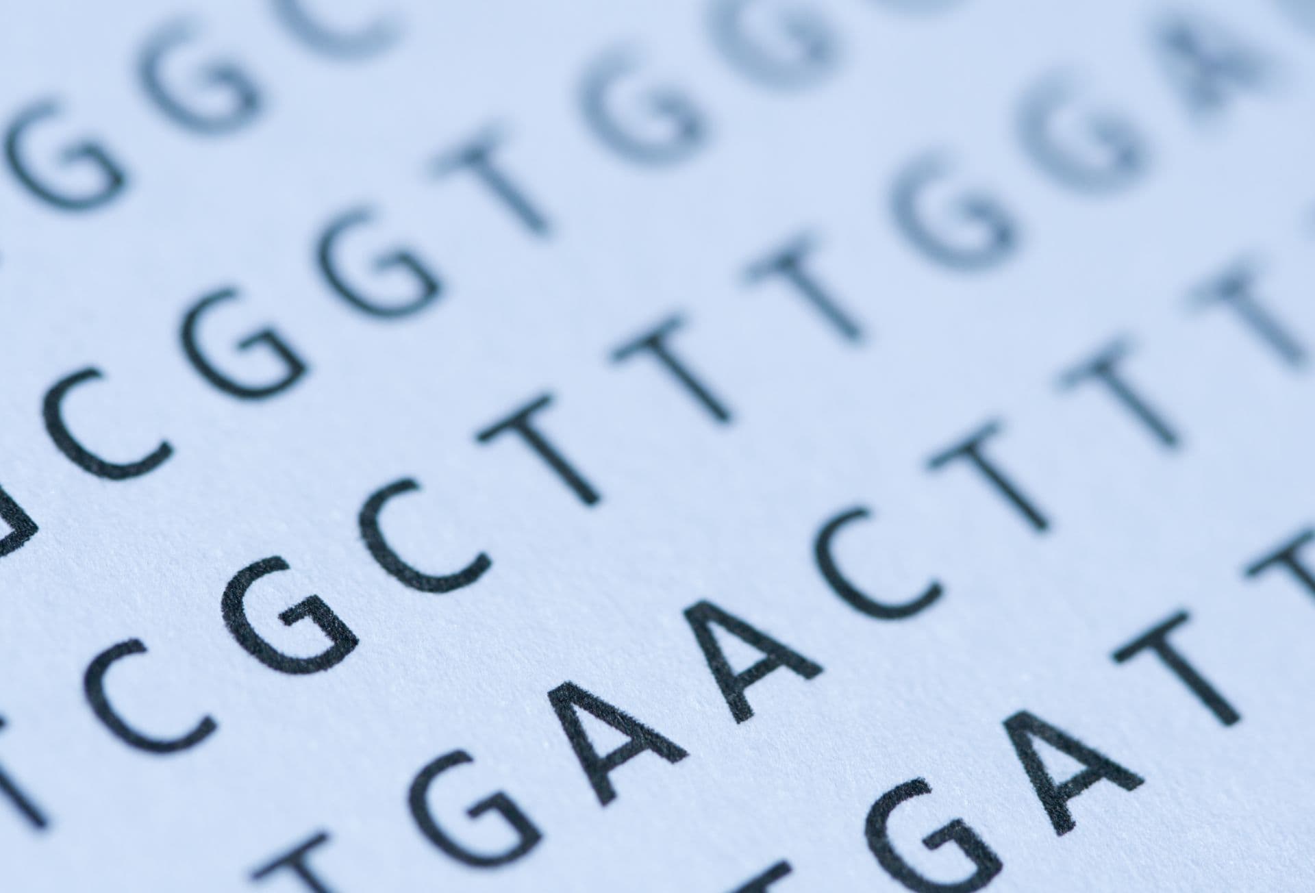 Macro of blue-tinted DNA nucleotide sequence printout on paper