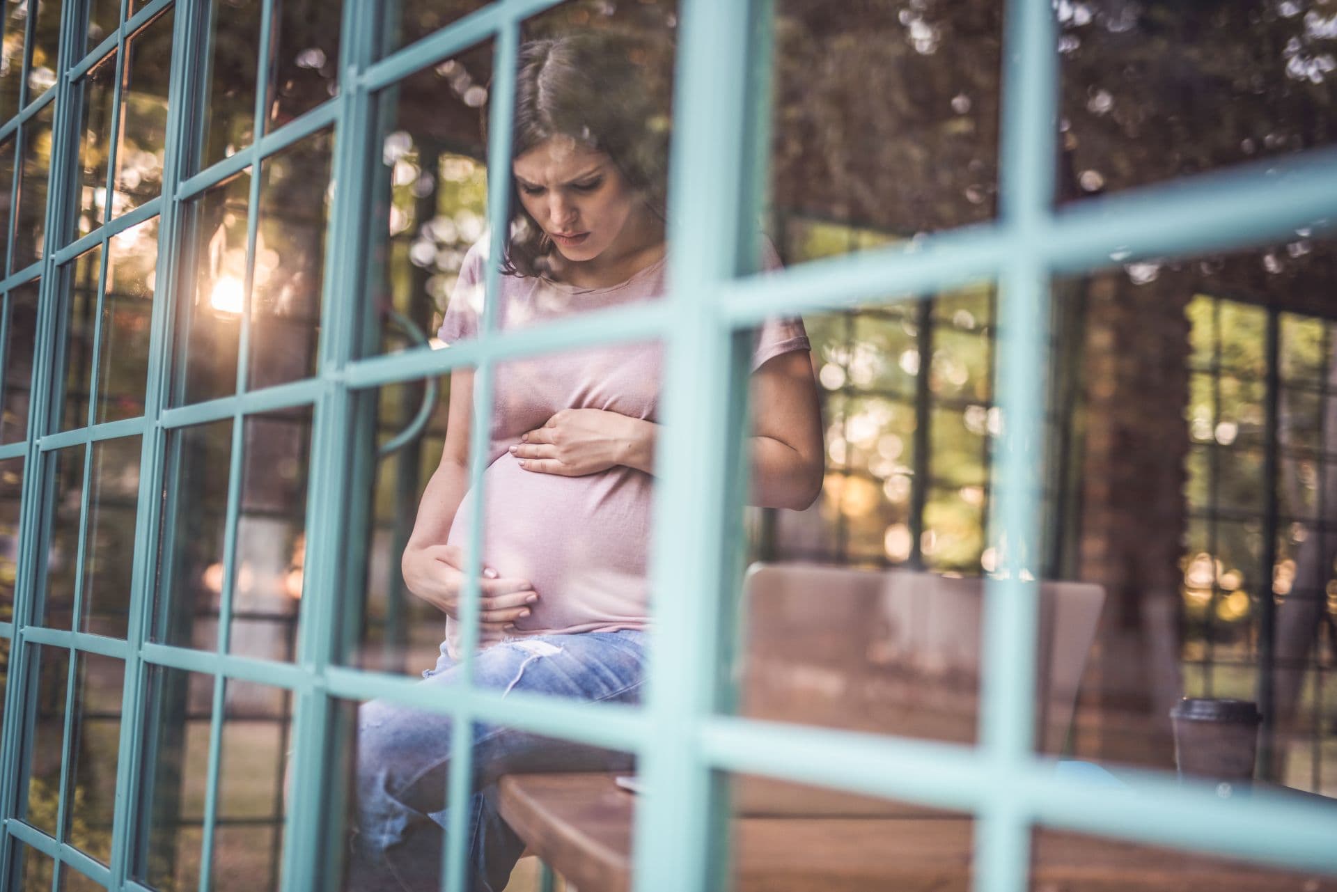Worried pregnant woman holding her belly with care.