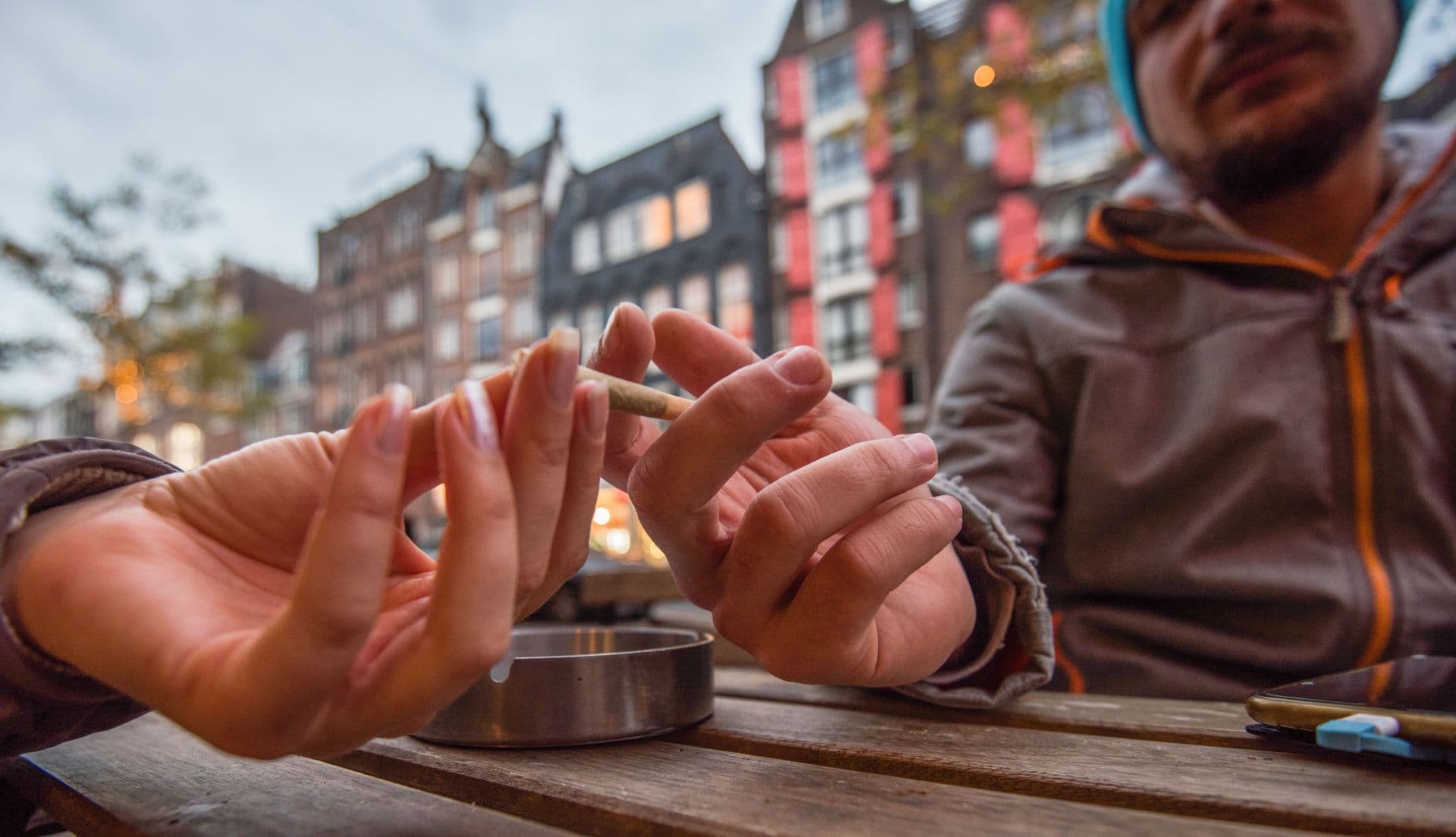 Close up of two unknown people sharing marijuana - joint in cafe.