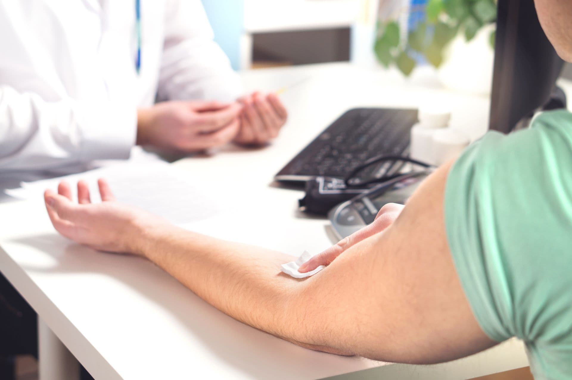 Blood test, sample or donation concept. Doctor with patient in hospital office, emergency room or laboratory. Person holding swab on arm after injection. Nurse holding needle.