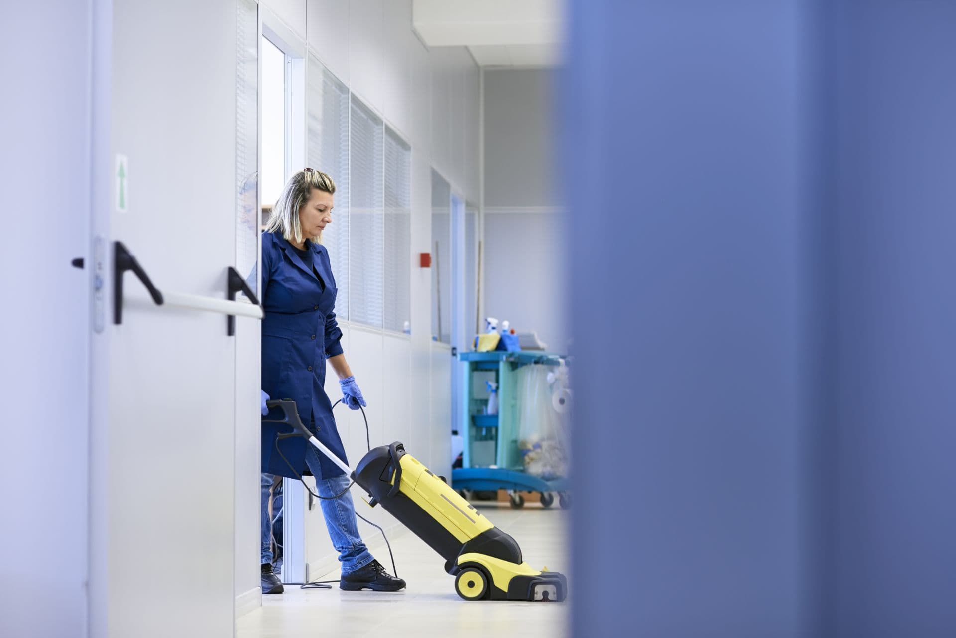 Frauenarbeit, professionelles Dienstmädchen, das Boden mit Maschinen im Industriegebäude reinigt und wäscht. Kopierraum in voller Länge