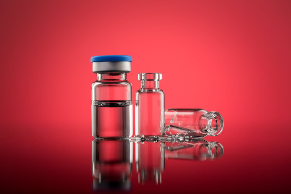 Vials with broken glass on red Background