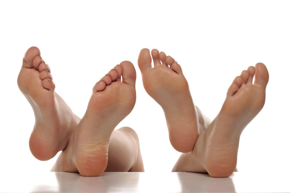 Two pairs od a beautiful well-groomed women&#8217;s sole feet close-up on a white isolated background, The concept of foot skin care