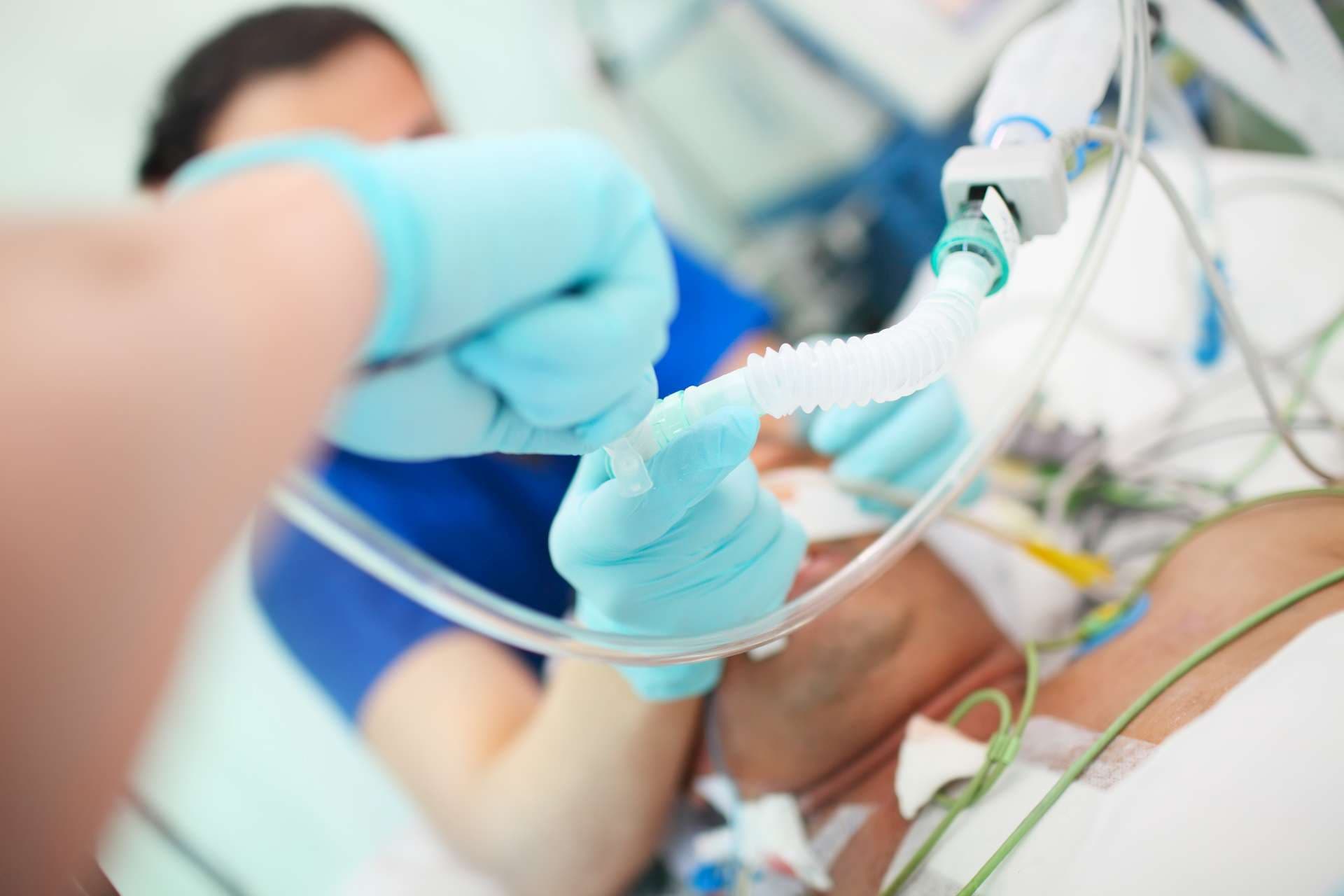 Arzt mit Assistent intubiert männlichen Patienten auf der Intensivstation.