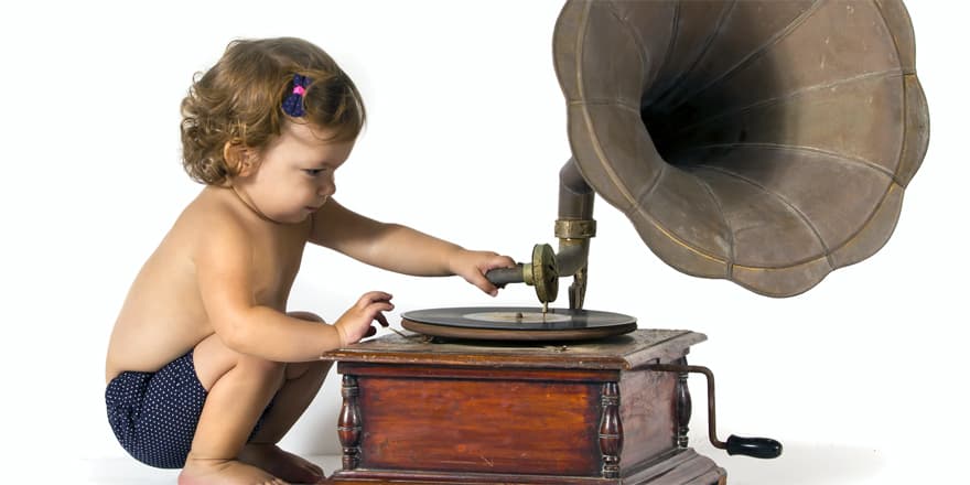 Baby sits and plays with an old gramophone