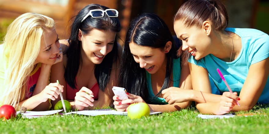 group of happy college girls chatting in network on green lawn