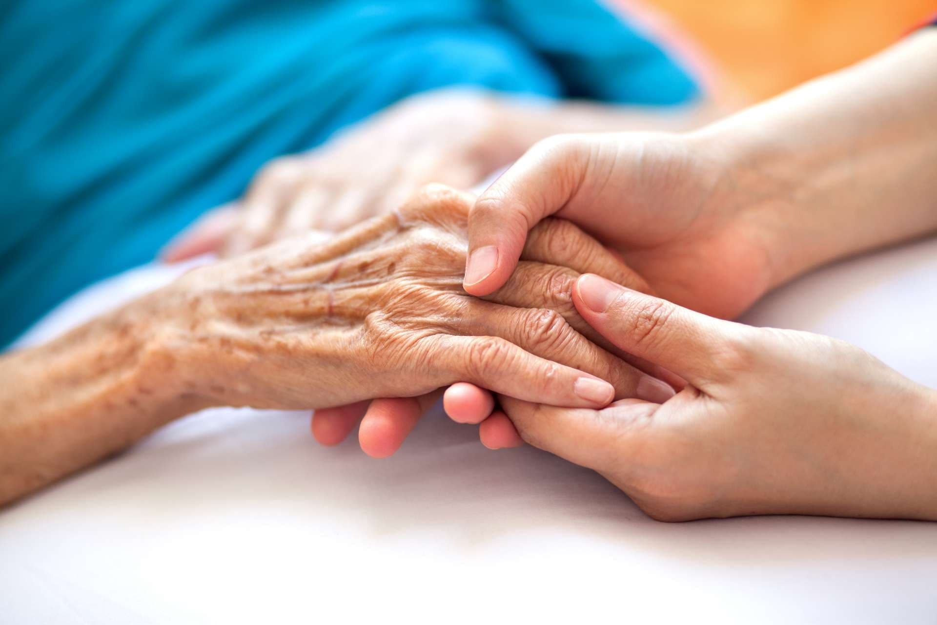 Frau, die die Hand der älteren Frau auf dem Bett hält