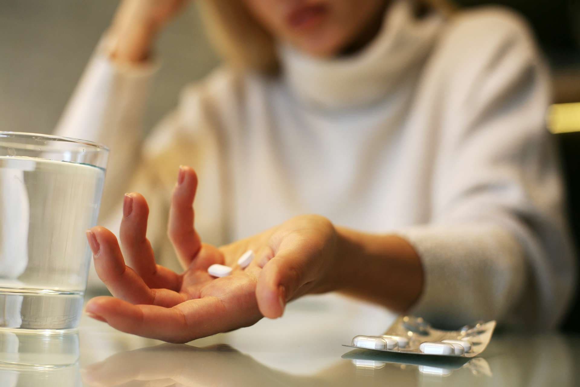 Schließen Sie oben von den Frauenhänden, die eine Pille halten.