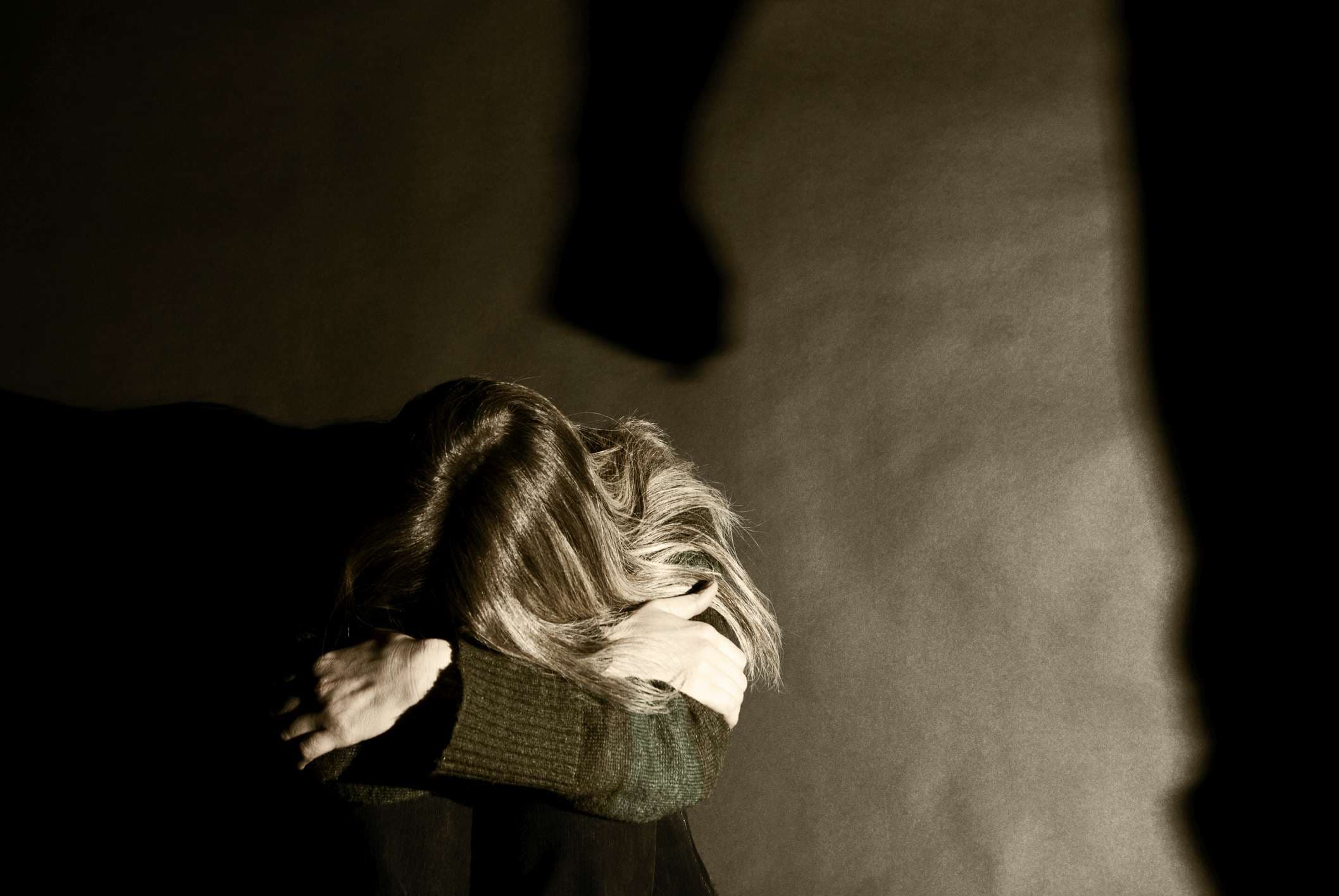 Unbekannte Frau mit Gewalt von einem Mann bedroht. Schatten des Mannes reflektiert. Leichter Sepia-Ton gegeben. Siehe auch