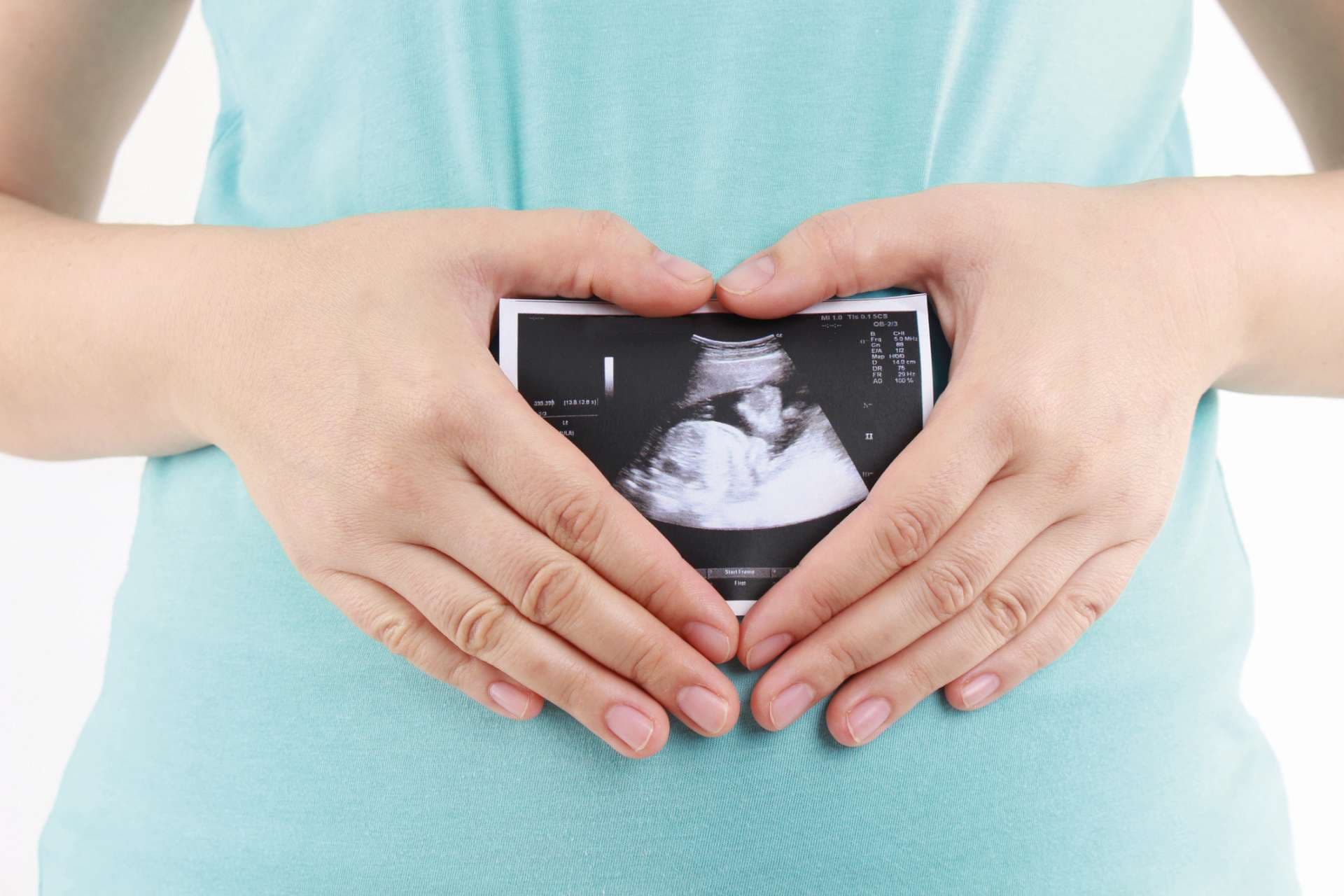 Pregnant woman is holding her stomach and a photo of her Ultrasound