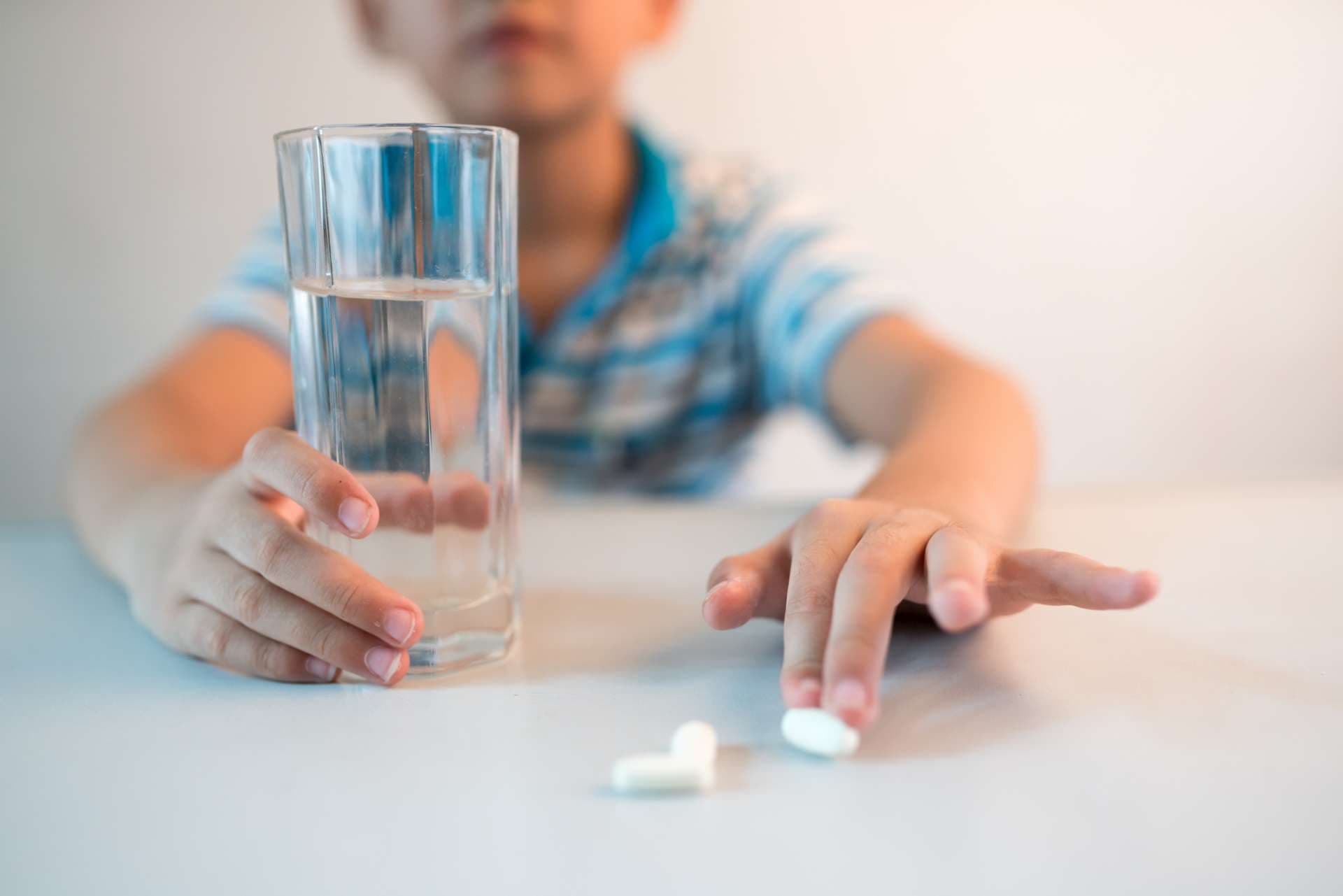 asian boy with cup of water and medicine in hand