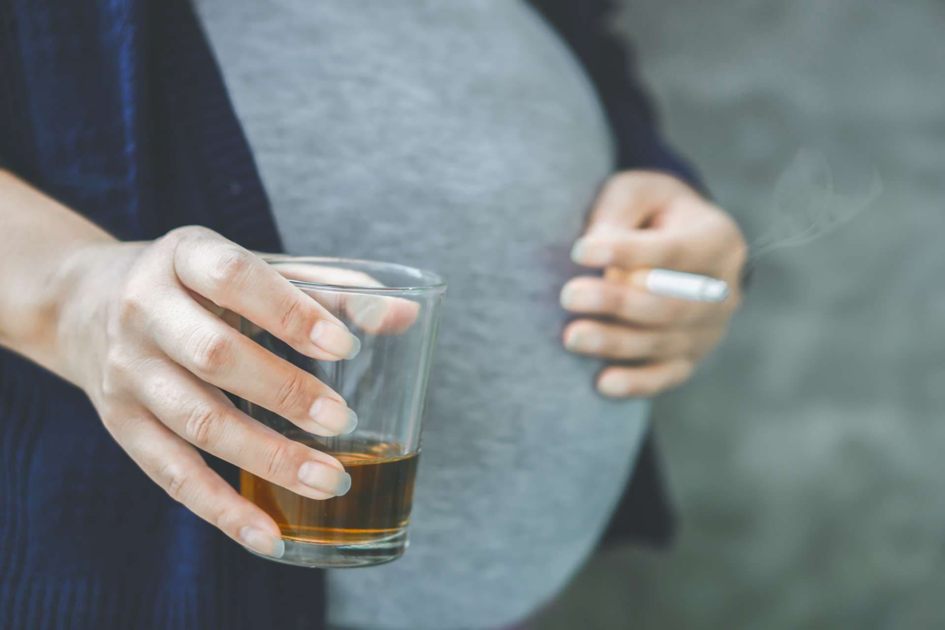 careless pregnant Asian woman hand drinking glass of alcohol and smoking cigarette