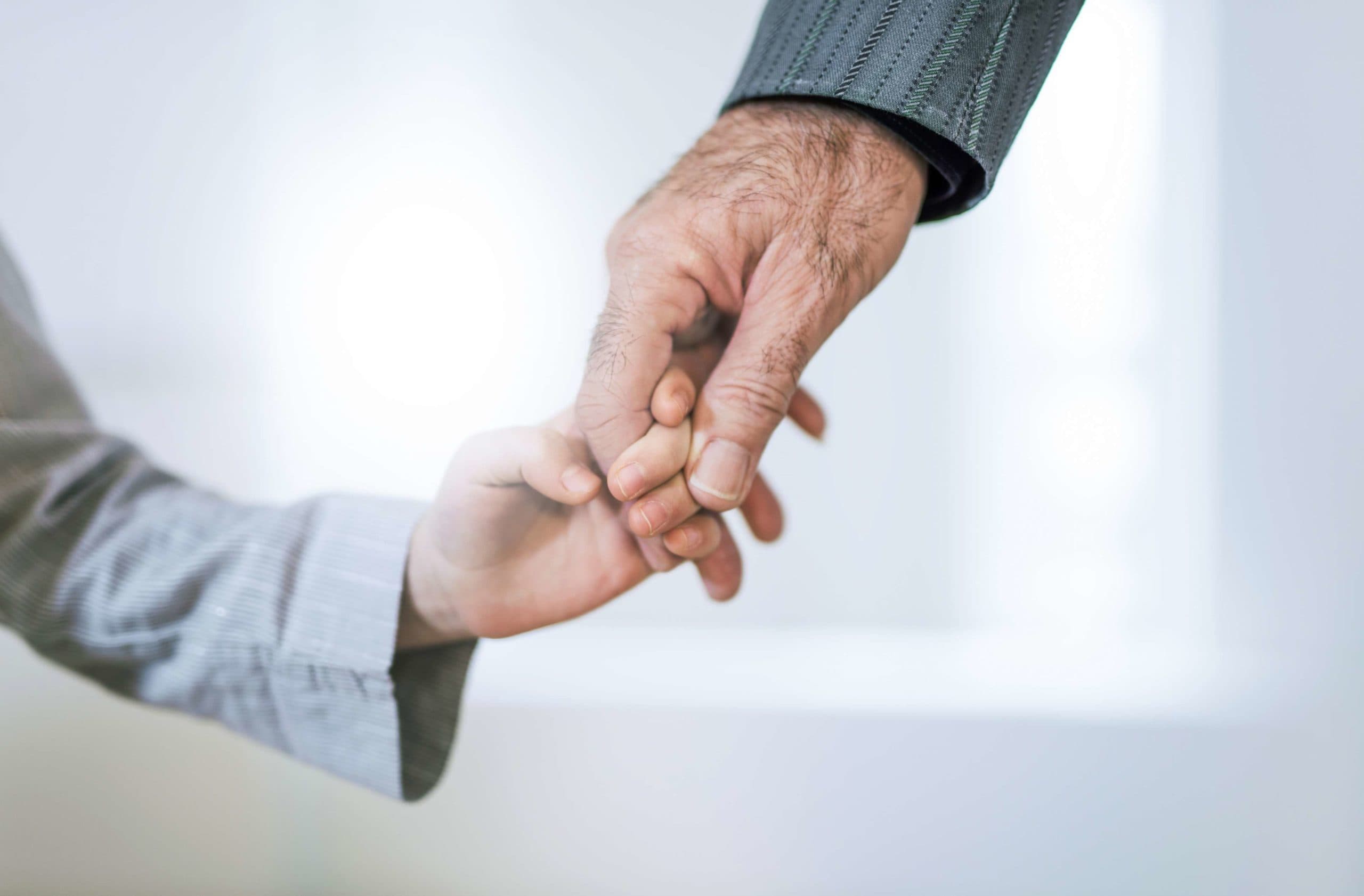 Hand Nahaufnahme von Großvater und Enkelin Händchen haltend.