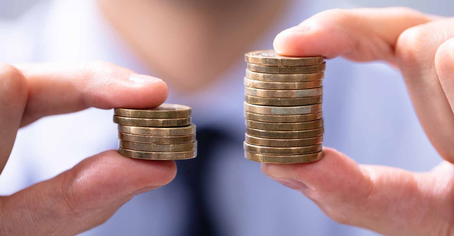Man Holding Two Coin Stacks To Compare