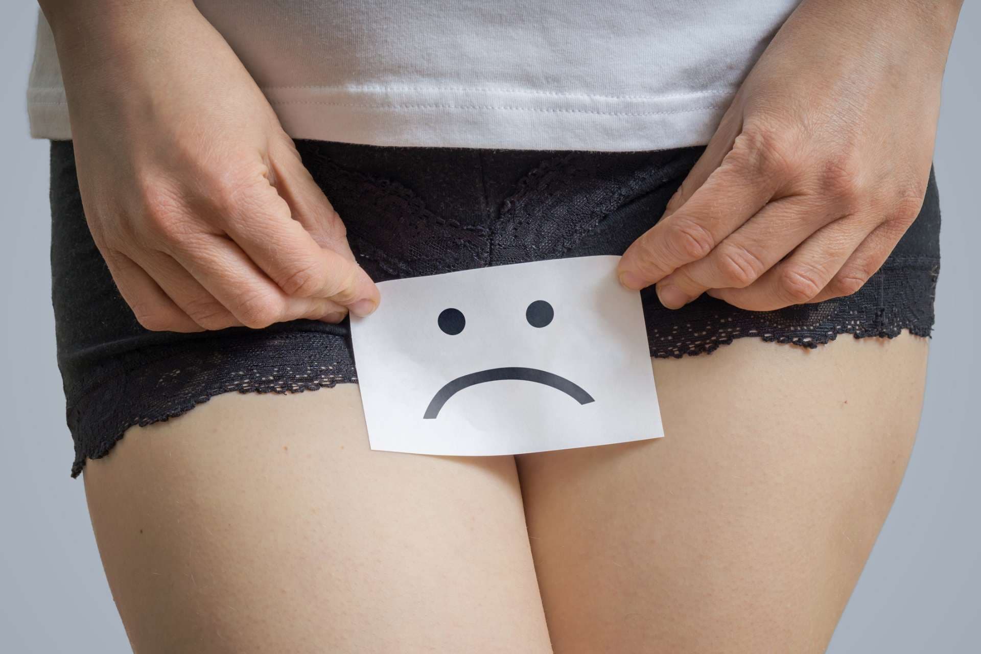 Konzept für vaginale oder menstruelle Probleme. Junge Frau hält Papier mit SOS über Schritt.