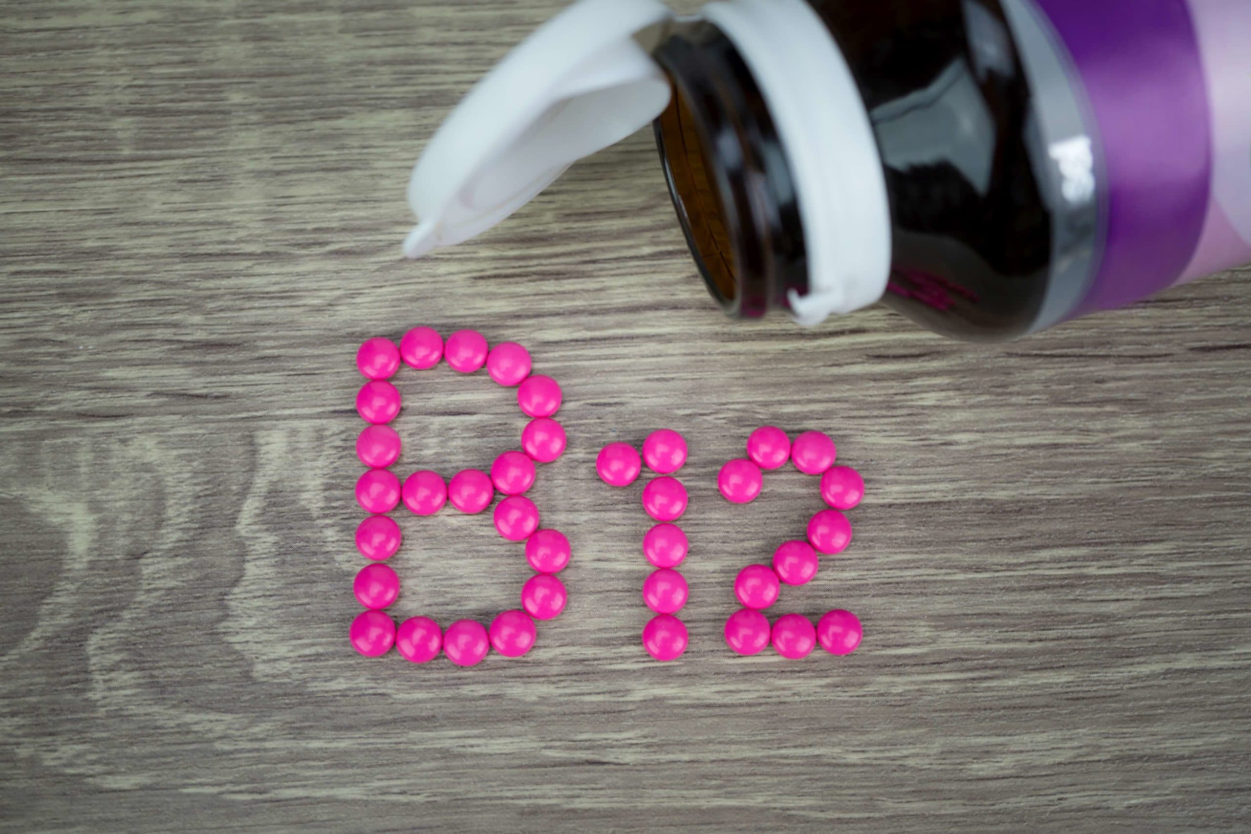 Rosa Pillen, die Form zu B12-Alphabet auf Holzhintergrund bilden