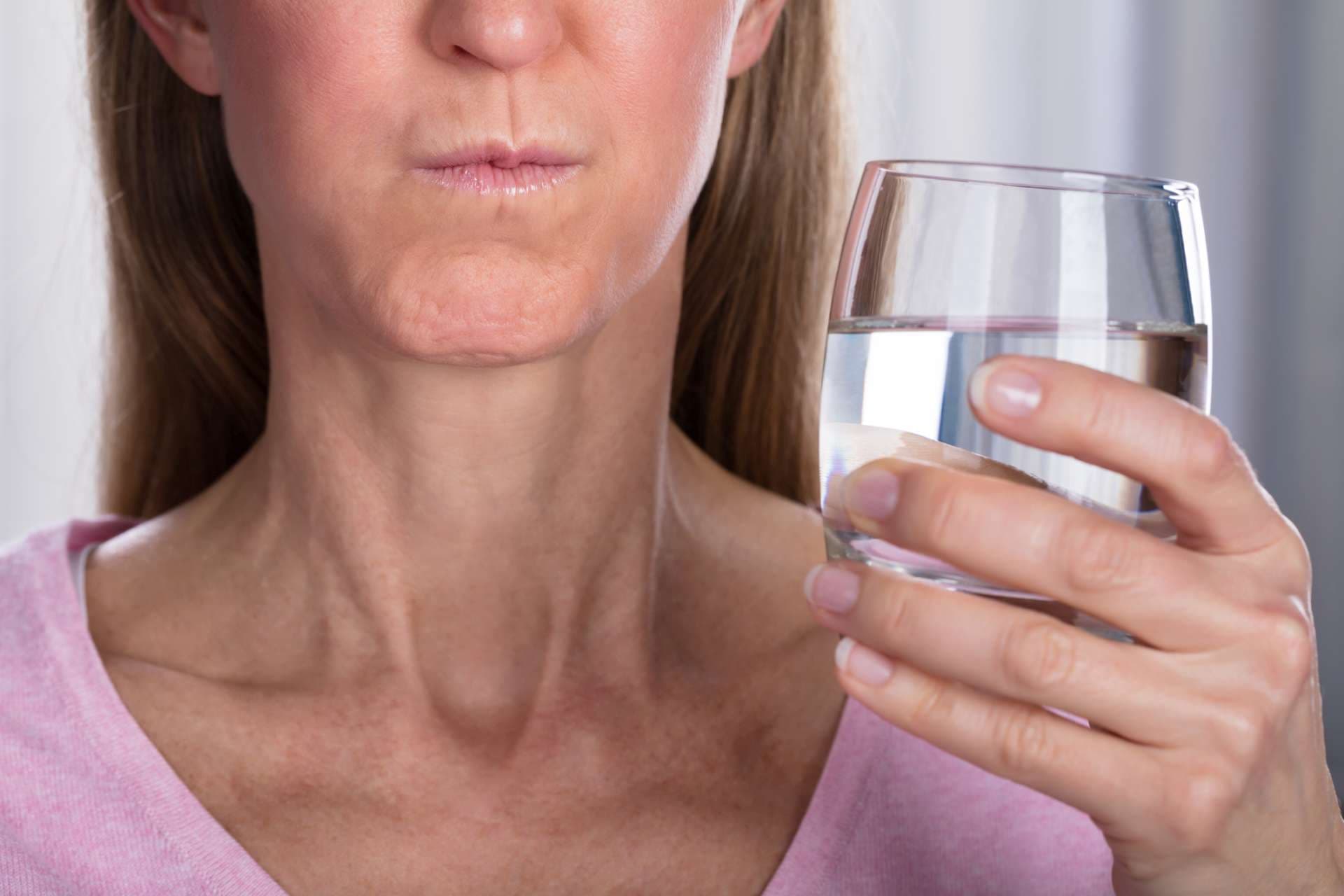 Nahaufnahme der Frau, die mit Wasser im Glas spült und gurgelt