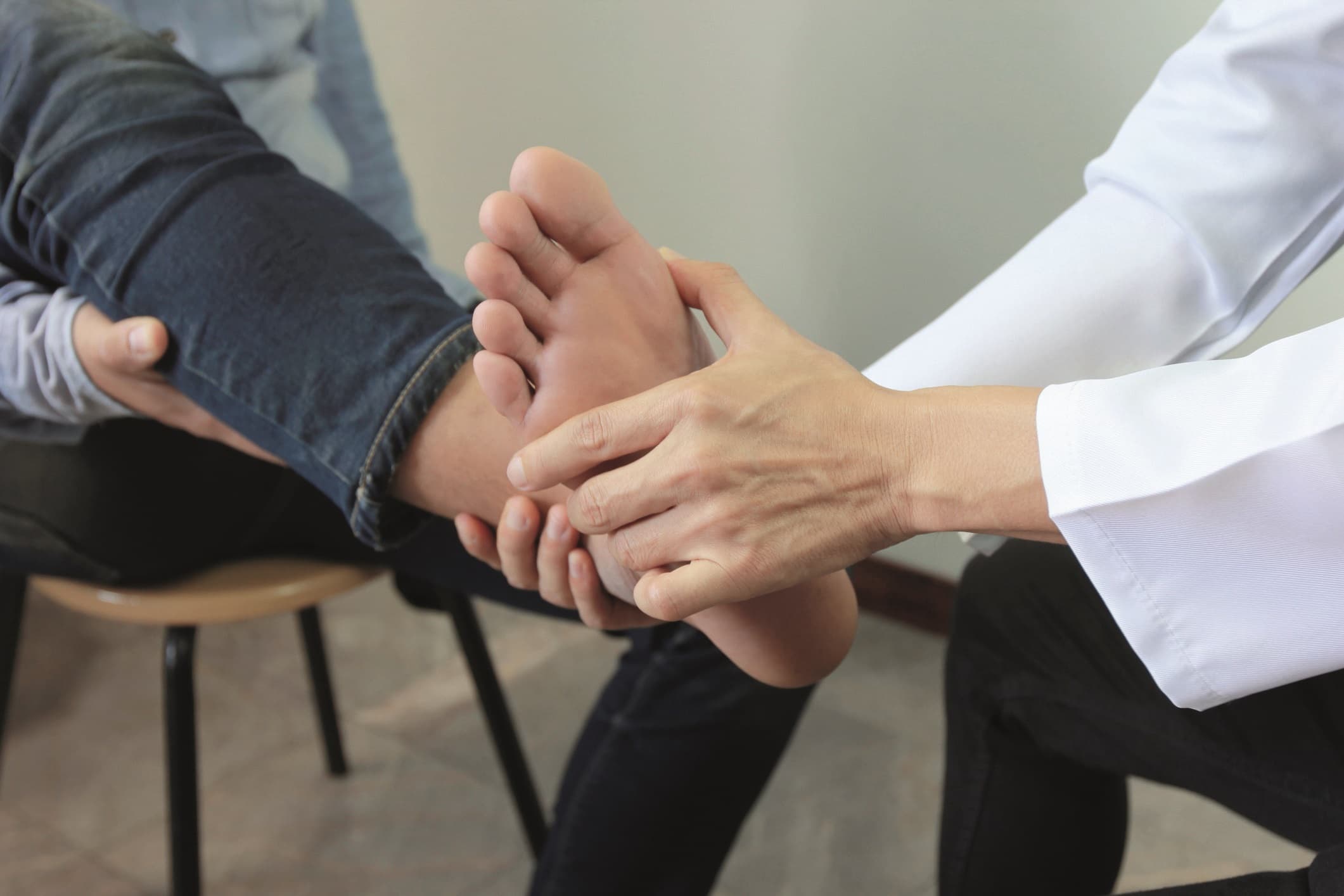 Closeup of Man feeling pain in her foot and doctor the traumatologist examines or treatment on white background, Healthy concept