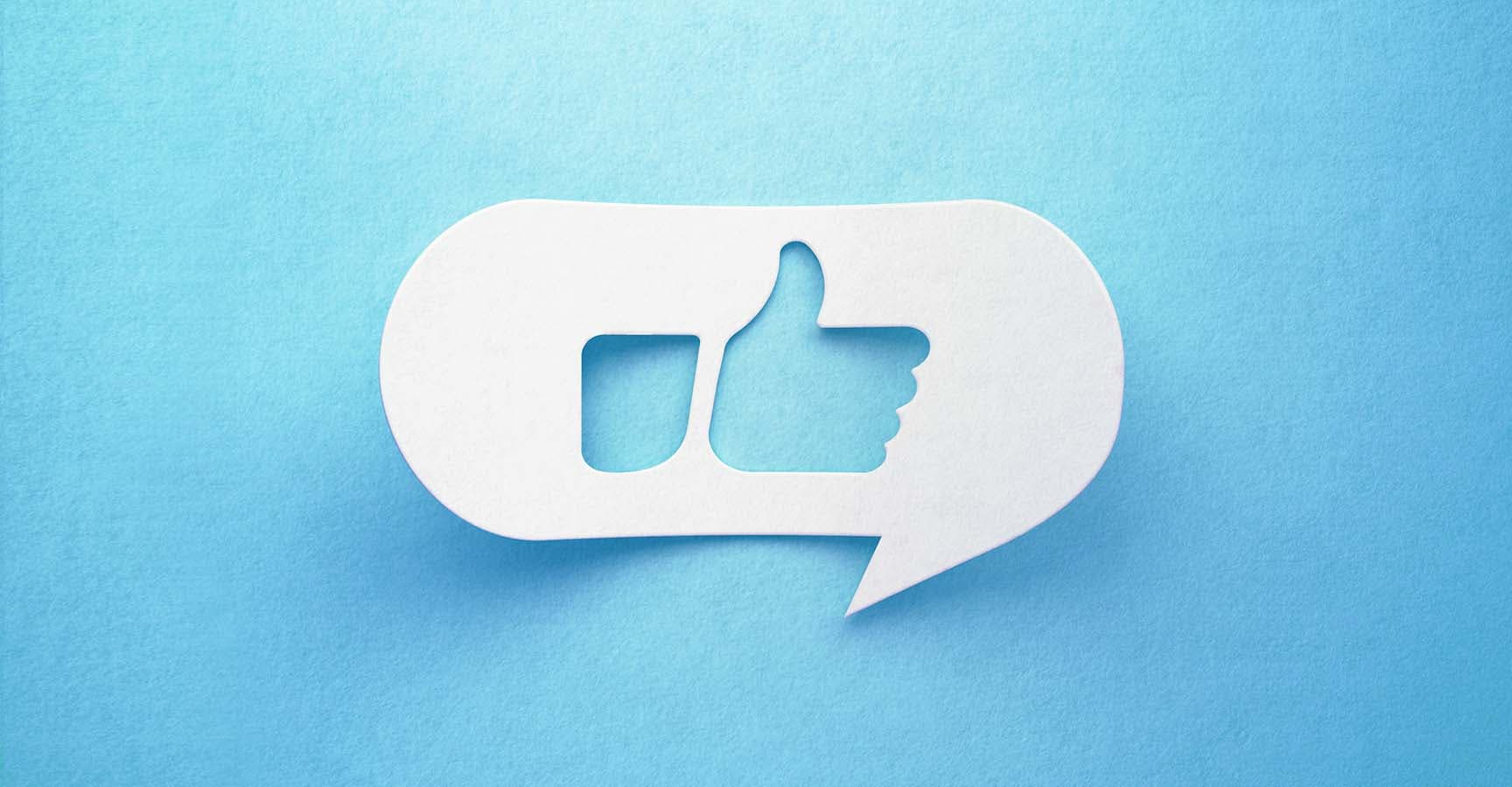 Thumbs up drawn white chat bubble on blue background. Horizontal composition with copy space. Social media like concept.