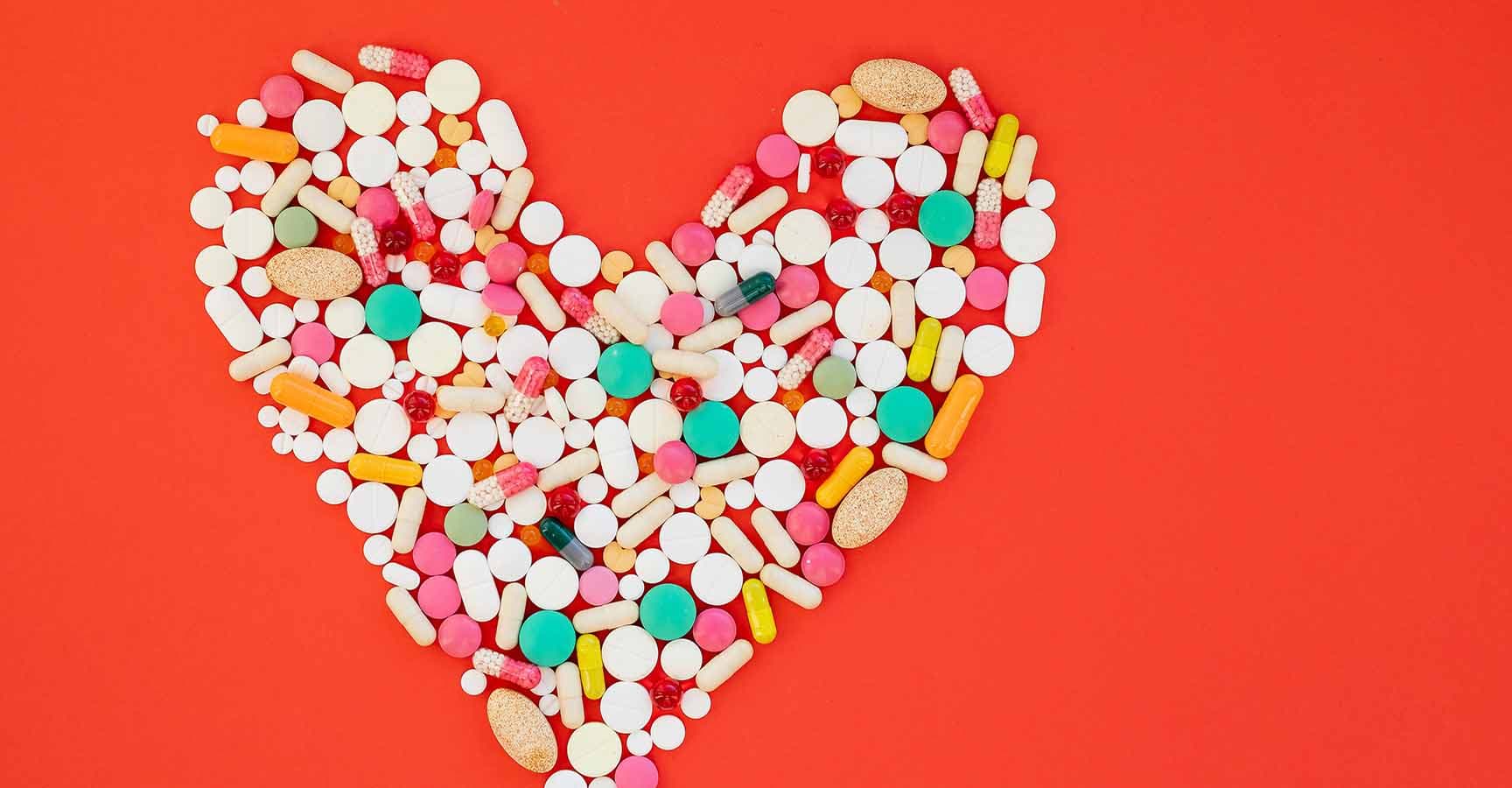 Danger for heart, medication,many colorful pills, capsules on red background.OBESITY concept.