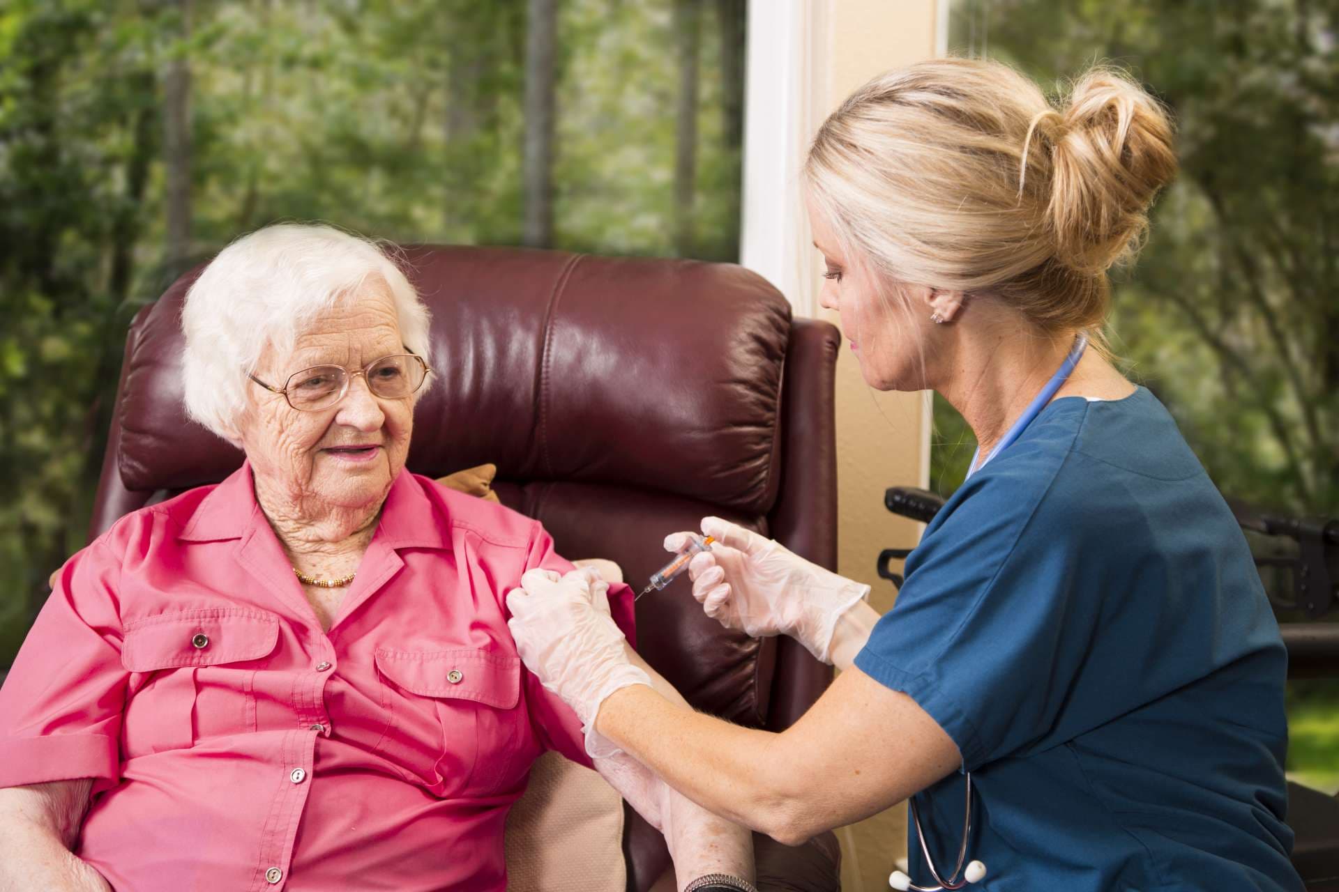 Krankenschwester im häuslichen Gesundheitswesen, die einer älteren Frau eine Injektion gibt.