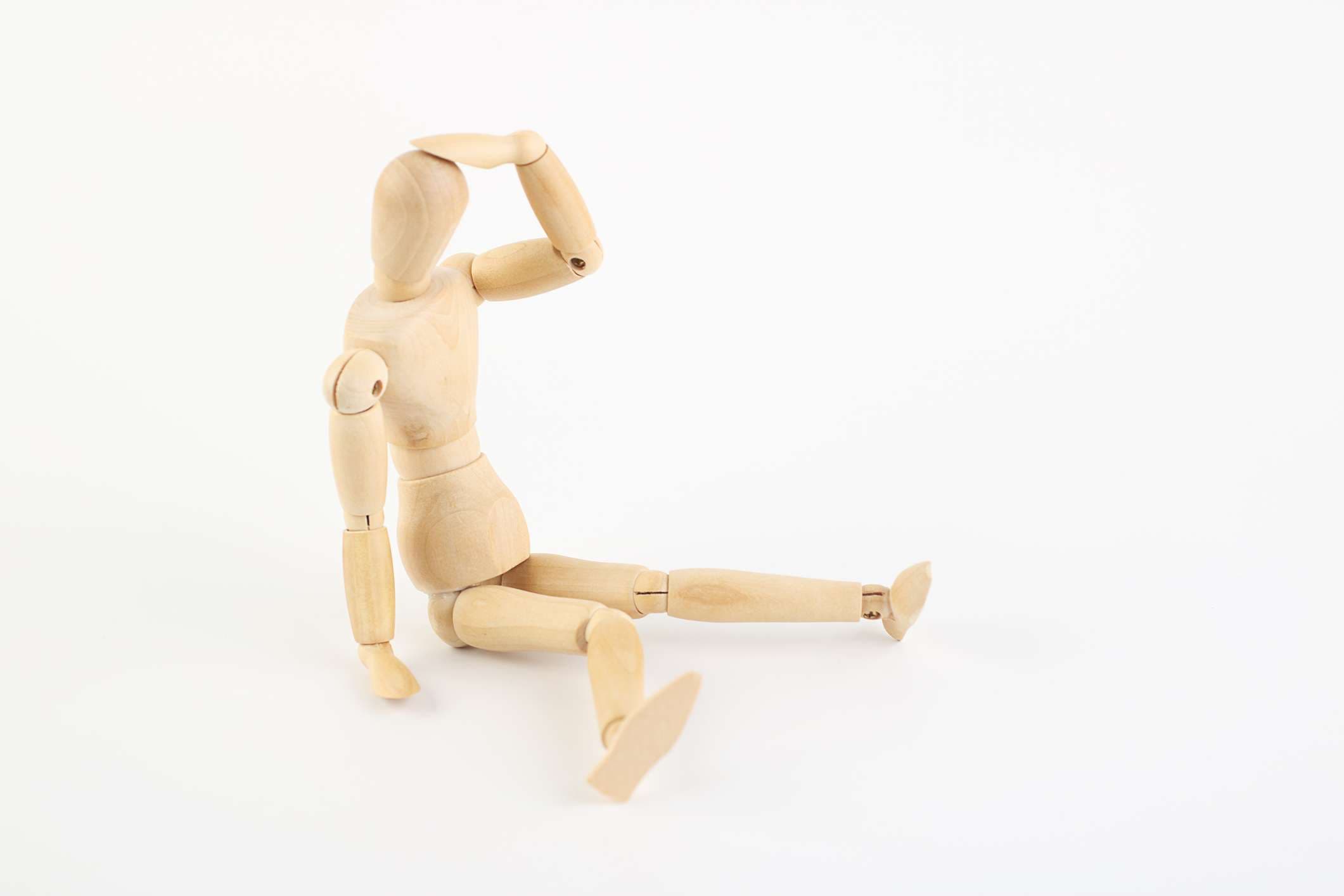 Depressive oder erschöpfte Holzpuppe sitzt auf dem Boden