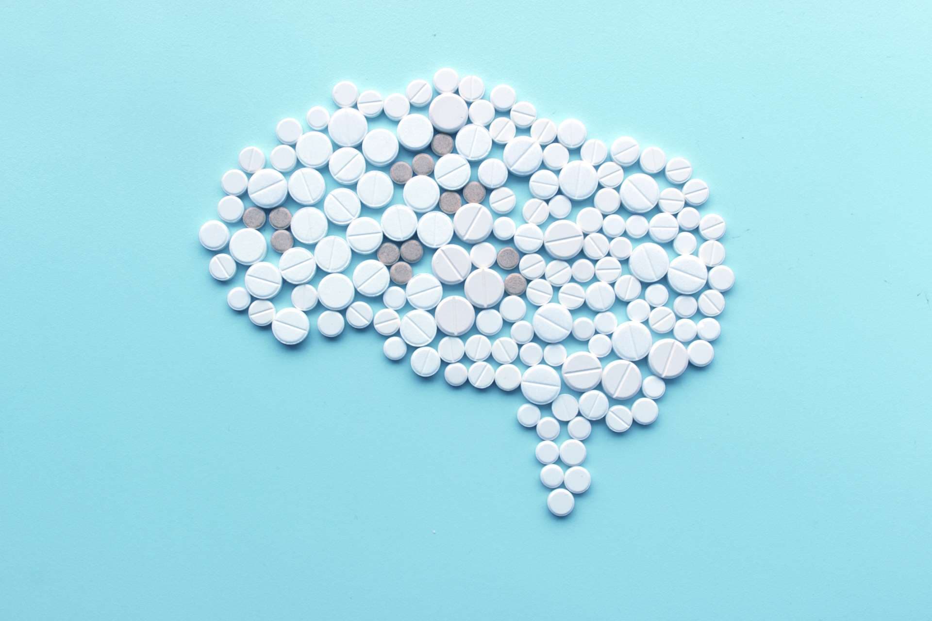 Gehirn Darstellung aus Tabletten und Pillen vor türkisem Hintergrund