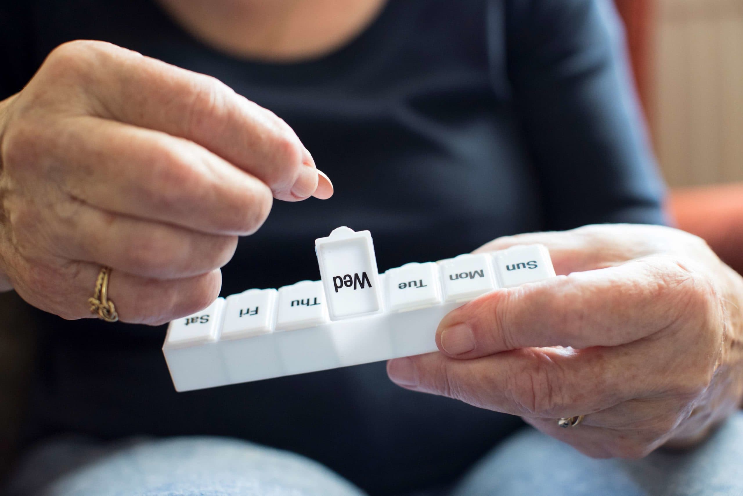 Ältere Frau, die Medikamente aus der Pillendose nimmt