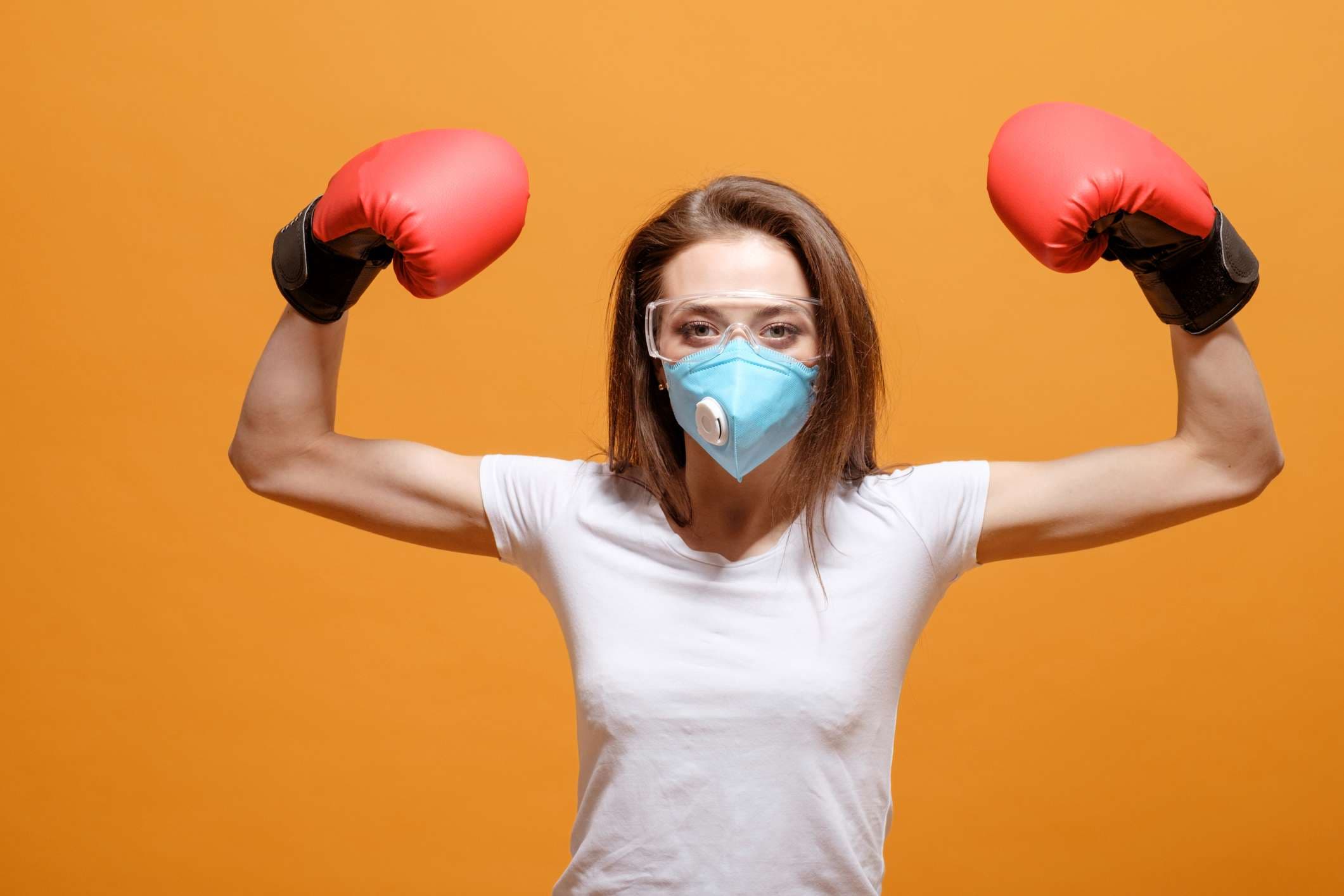 woman in boxing gloves, home quarantine, coronavirus pandemic, on yellow orange background, battle fight with virus