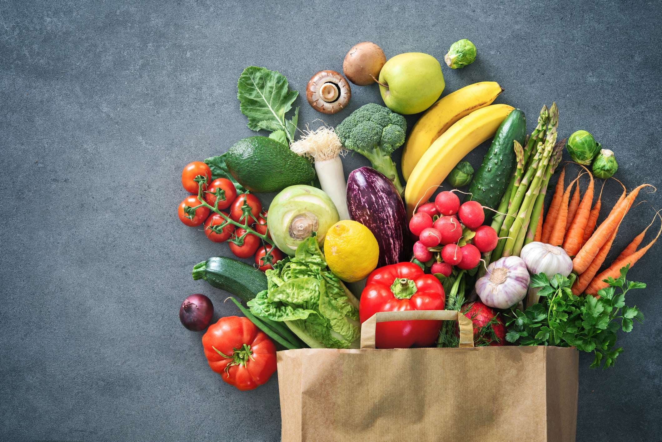 Gesunde Auswahl an Lebensmitteln. Einkaufstasche voller frischem Gemüse und Obst. Flach lag Essen auf dem Tisch