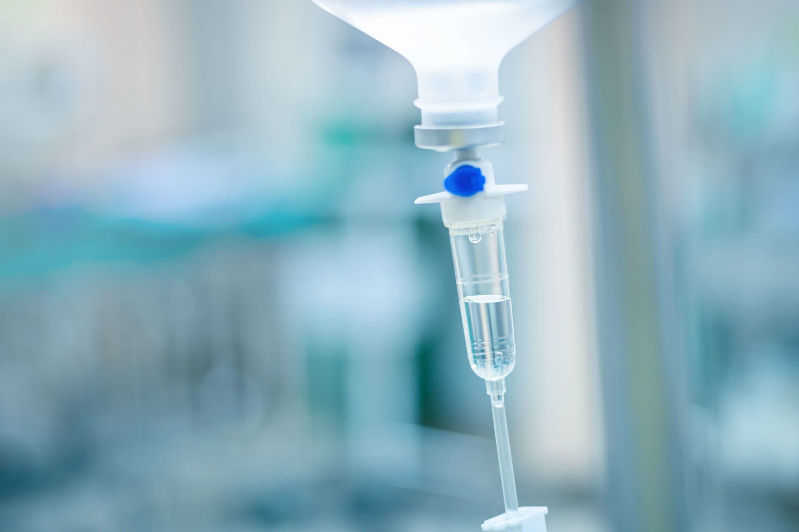 Intravenöse Therapie iv Infusionsset und Flasche auf einer Stange. Flüssige Kochsalzlösung tropft langsam Tropfen von Medikamenten, Medikamenten oder Antibiotika-Therapie und die Wiederherstellung von Operationen in einem Krankenhaus oder einer Klinik