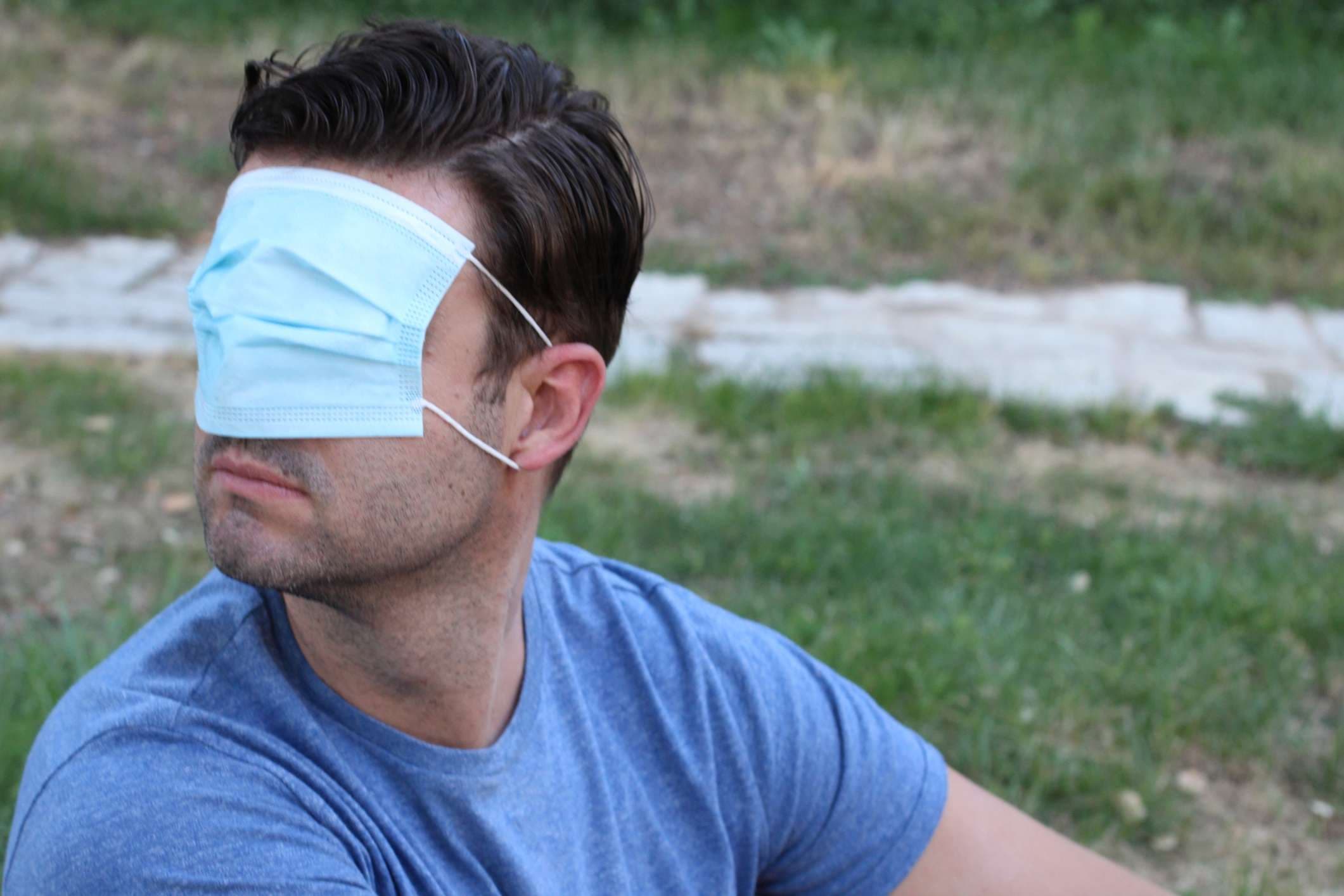Mann, der seine Vision mit chirurgischer Maske bedeckt.
