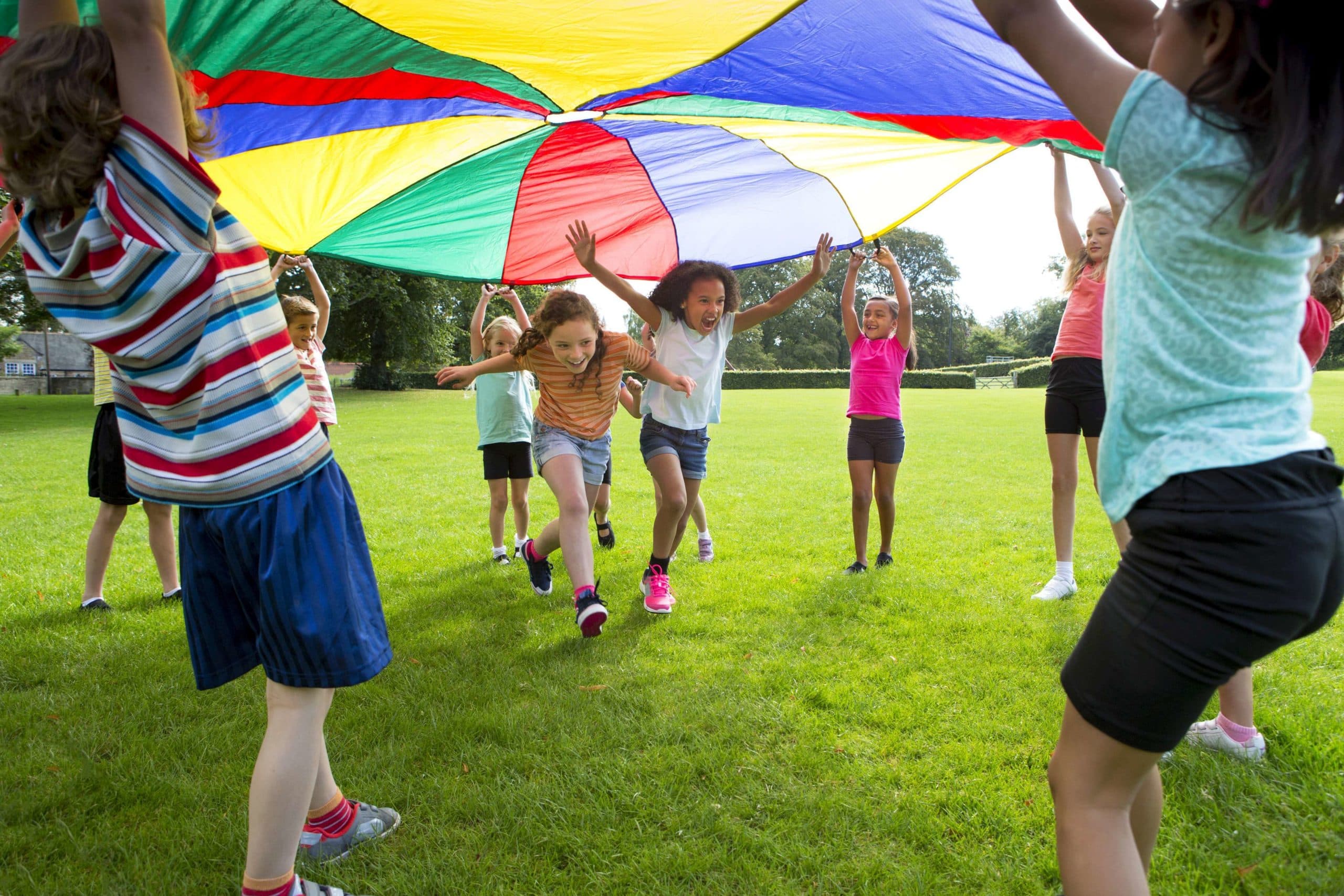 Kinder spielen mit einem bunten Fallschirm