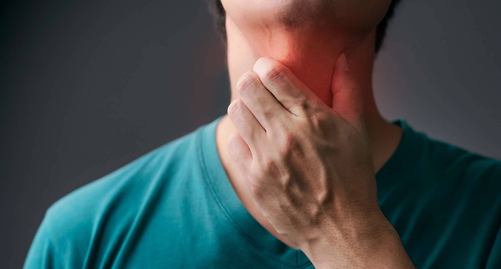 Unglücklicher asiatischer Mann, der seine Hand an seinem Hals berührt und an Drüsenentzündung leidet. Erwachsener Mann fühlt sich schlecht an Halsschmerzen und krank von Erkältung, Grippe. Halsschmerzen, Krankheit, Gesundheitswesen und medizinisches Konzept.