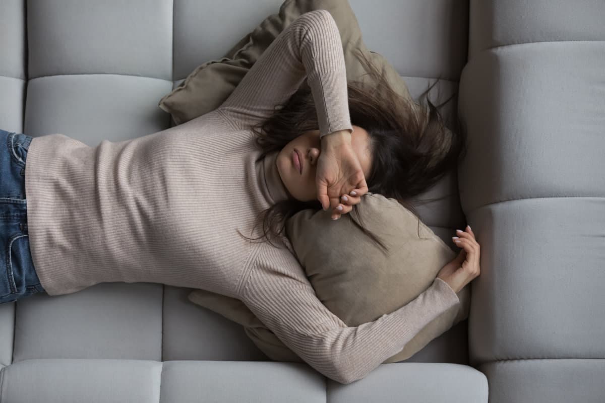 Friedliches Mädchen, das zu Hause auf dem Rücken auf einer bequemen Couch liegt