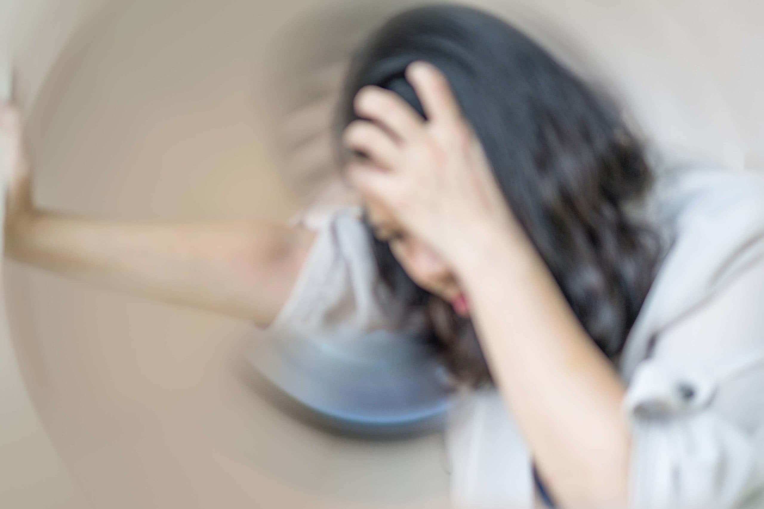 Konzept der Schwindelkrankheit. Unscharfe Hände der Frau auf dem Kopf, die Kopfschmerzen schwindelig machen, Schwindelgefühl, ein Problem mit dem Innenohr, dem Gehirn oder der sensorischen Nervenbahn.