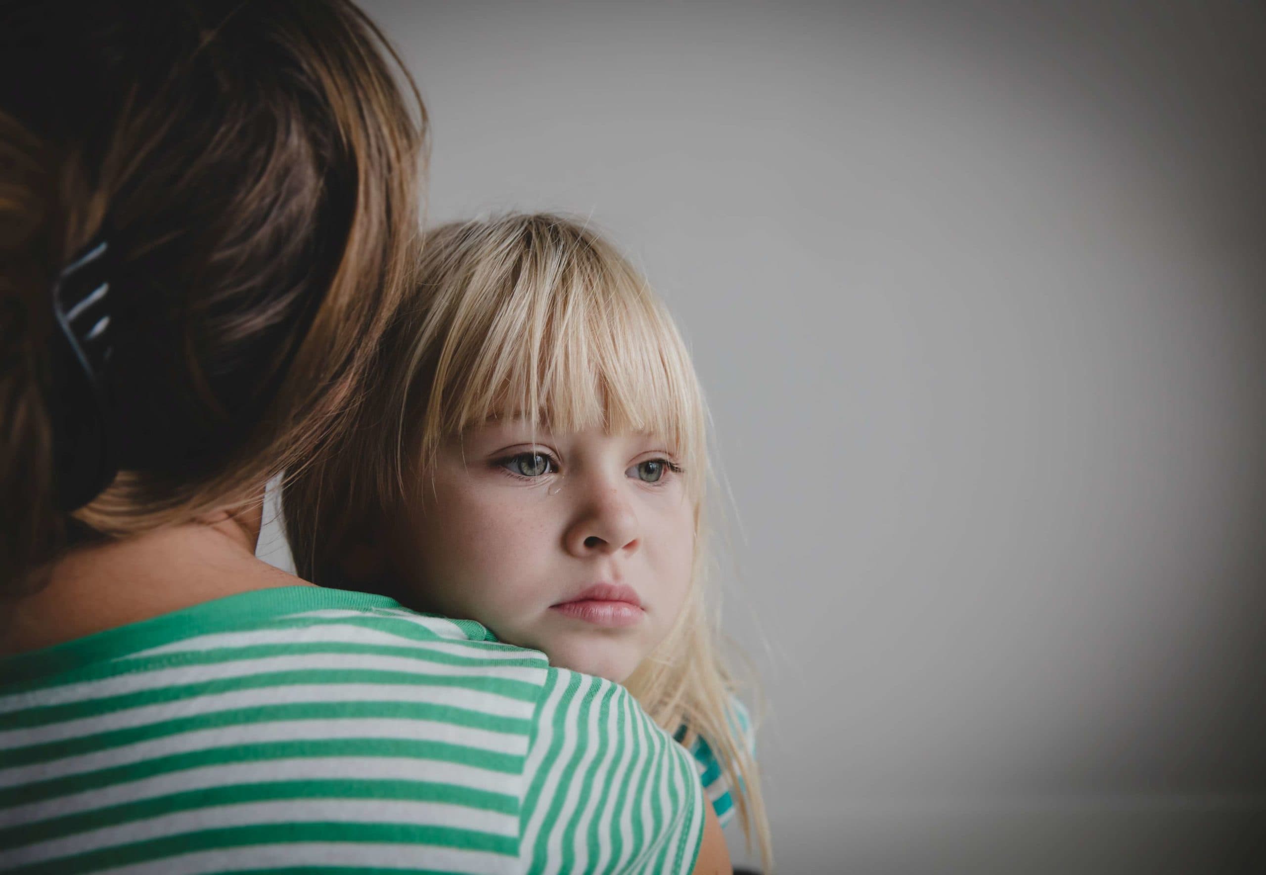 trauriges weinendes kleines Mädchen, das Mutter, Elternschaft und Schutz umarmt