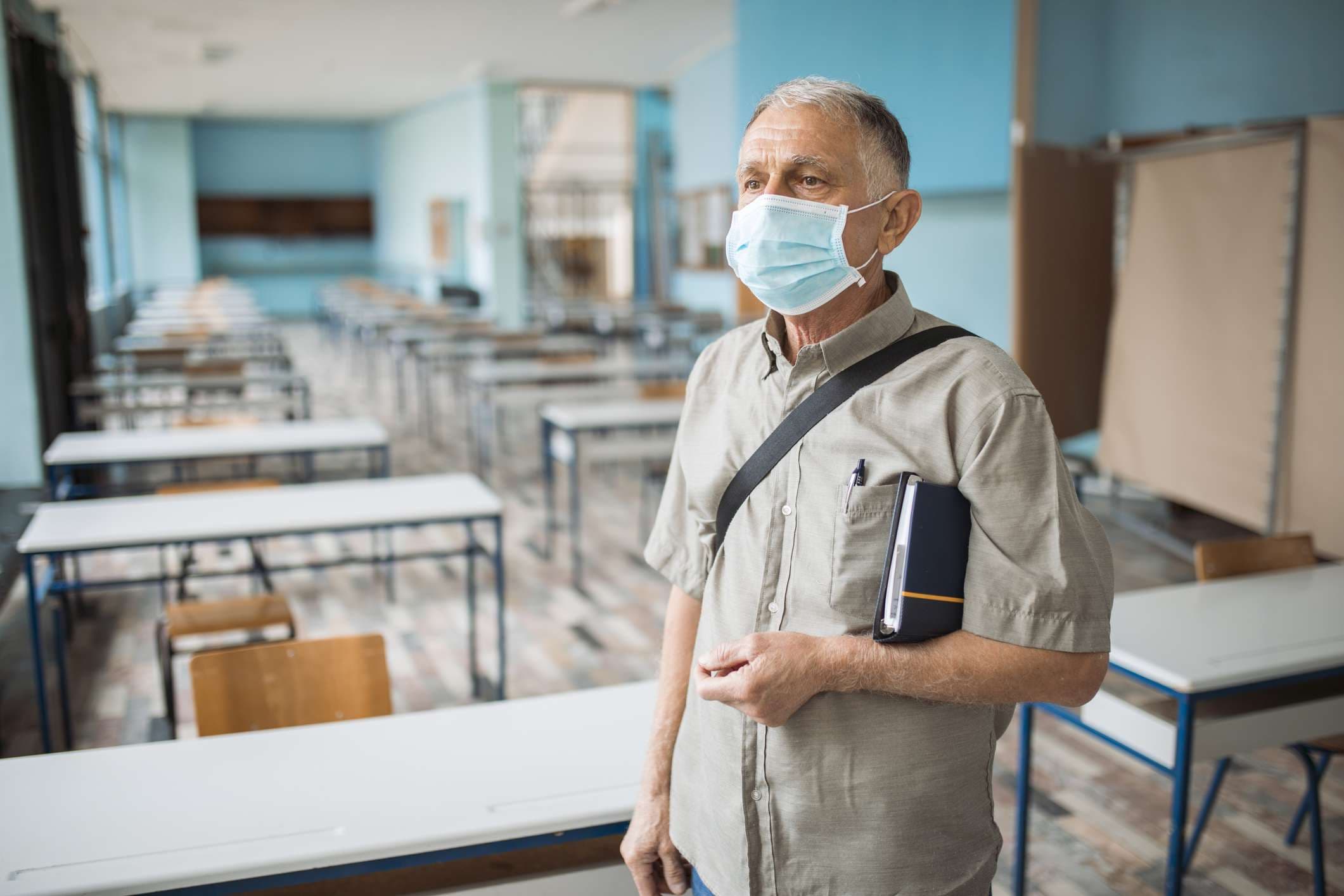 Porträt eines Professors in einem leeren Klassenzimmer mit Gesichtsmaske