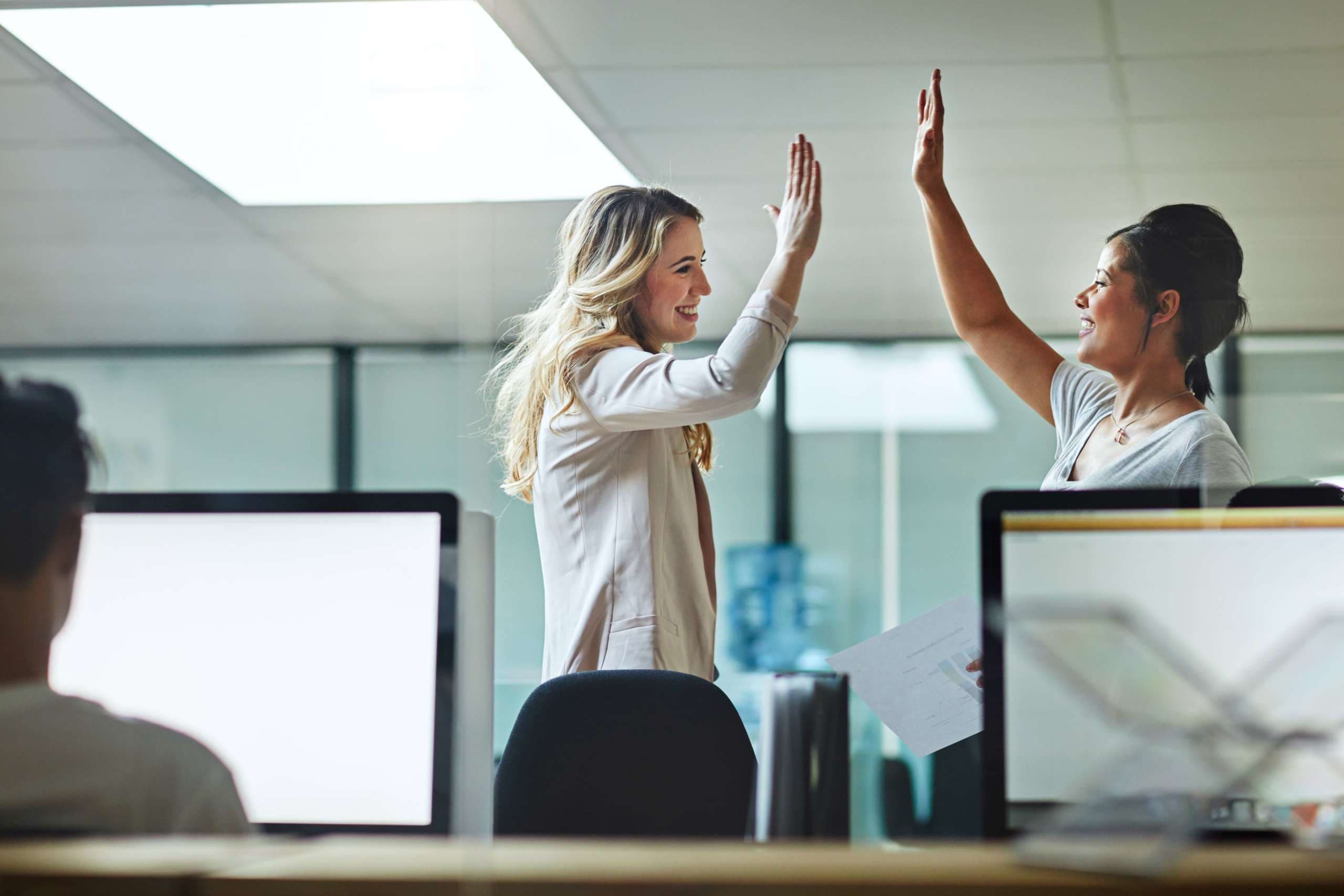 Aufnahme von zwei Kollegen, die sich bei der Arbeit ein High Five geben