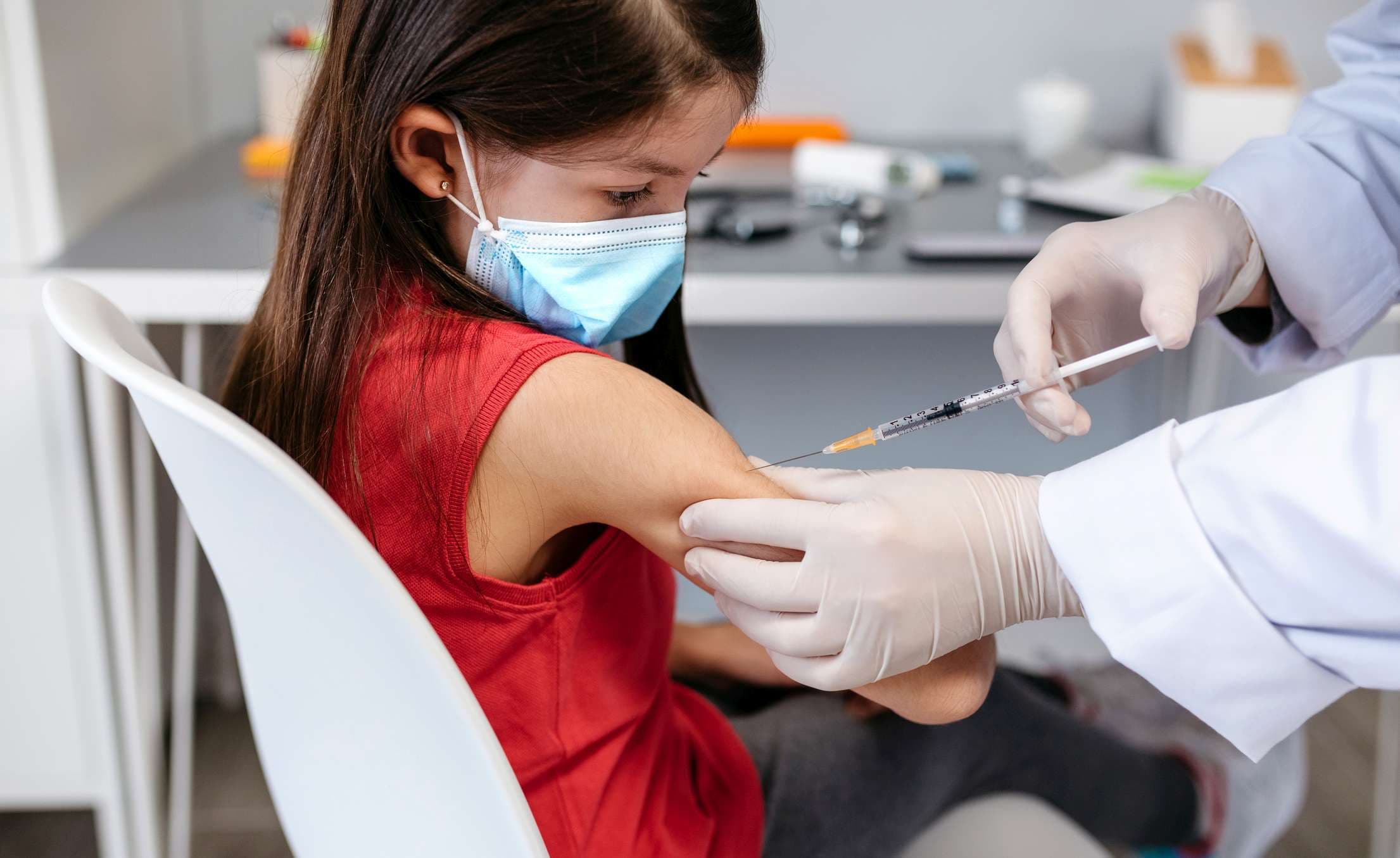 Kleines Mädchen, das in der Arztpraxis einen Coronavirus-Impfstoff erhält