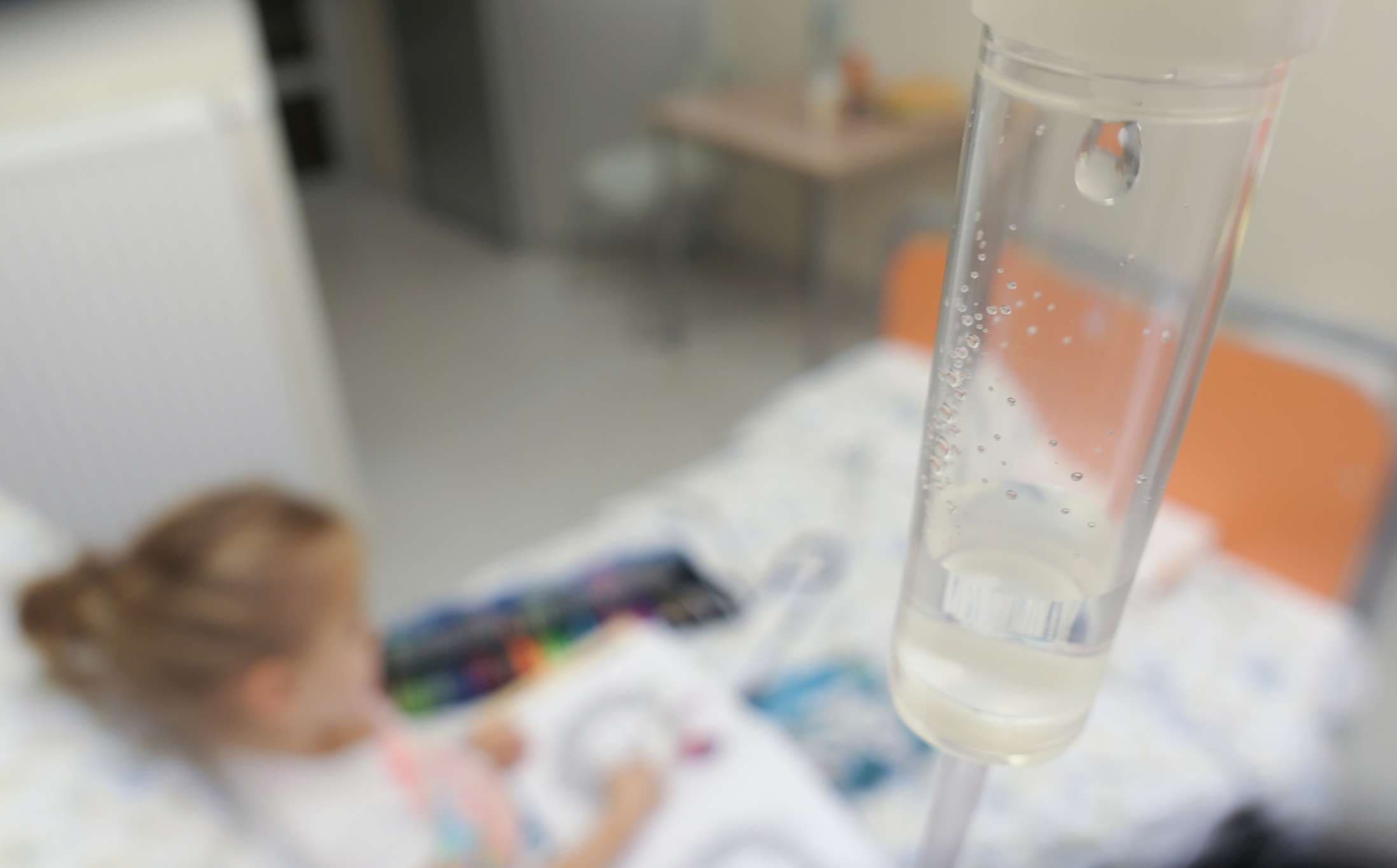Junges Mädchen auf einem Tropf mit peripherem Venenkatheter Lesebuch im Krankenhaus