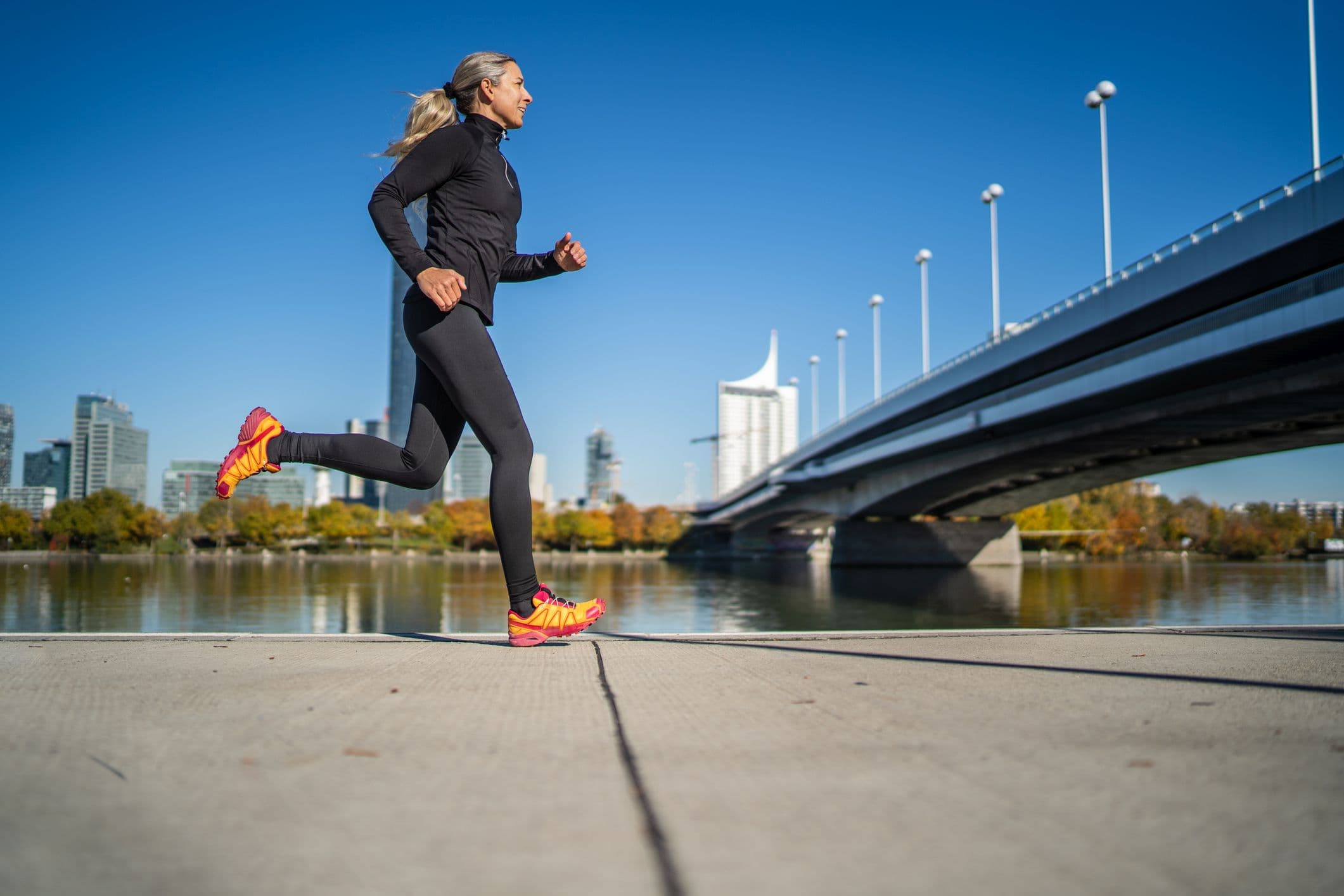 sportlerin, die entlang des flusses in der stadt läuft