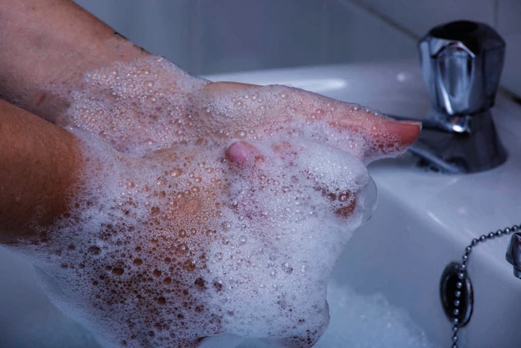 Eine Person wäscht die Hände mit Seife in einem Becken