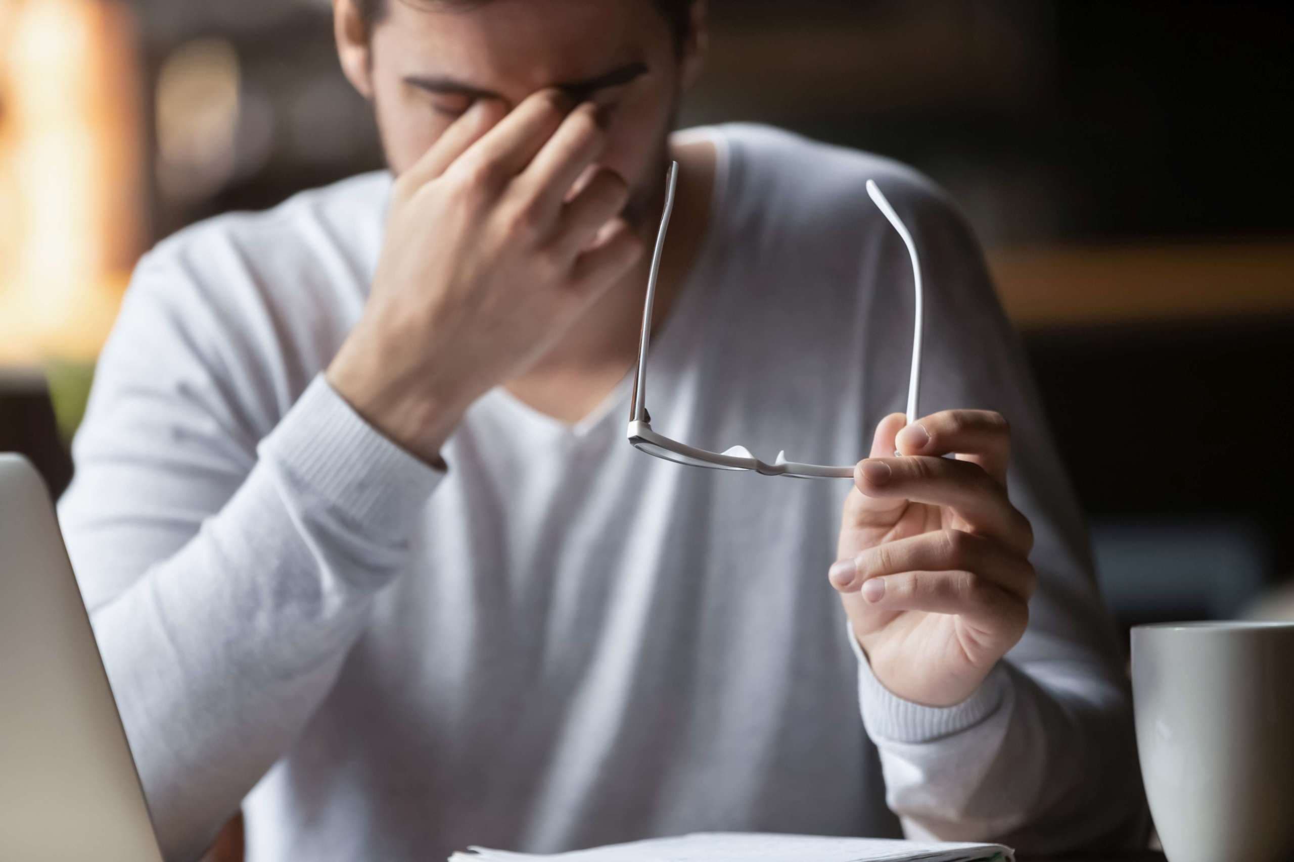 Müde von Computergeschäftsmann, der die Brille abnimmt, fühlt er sich überanstrengt